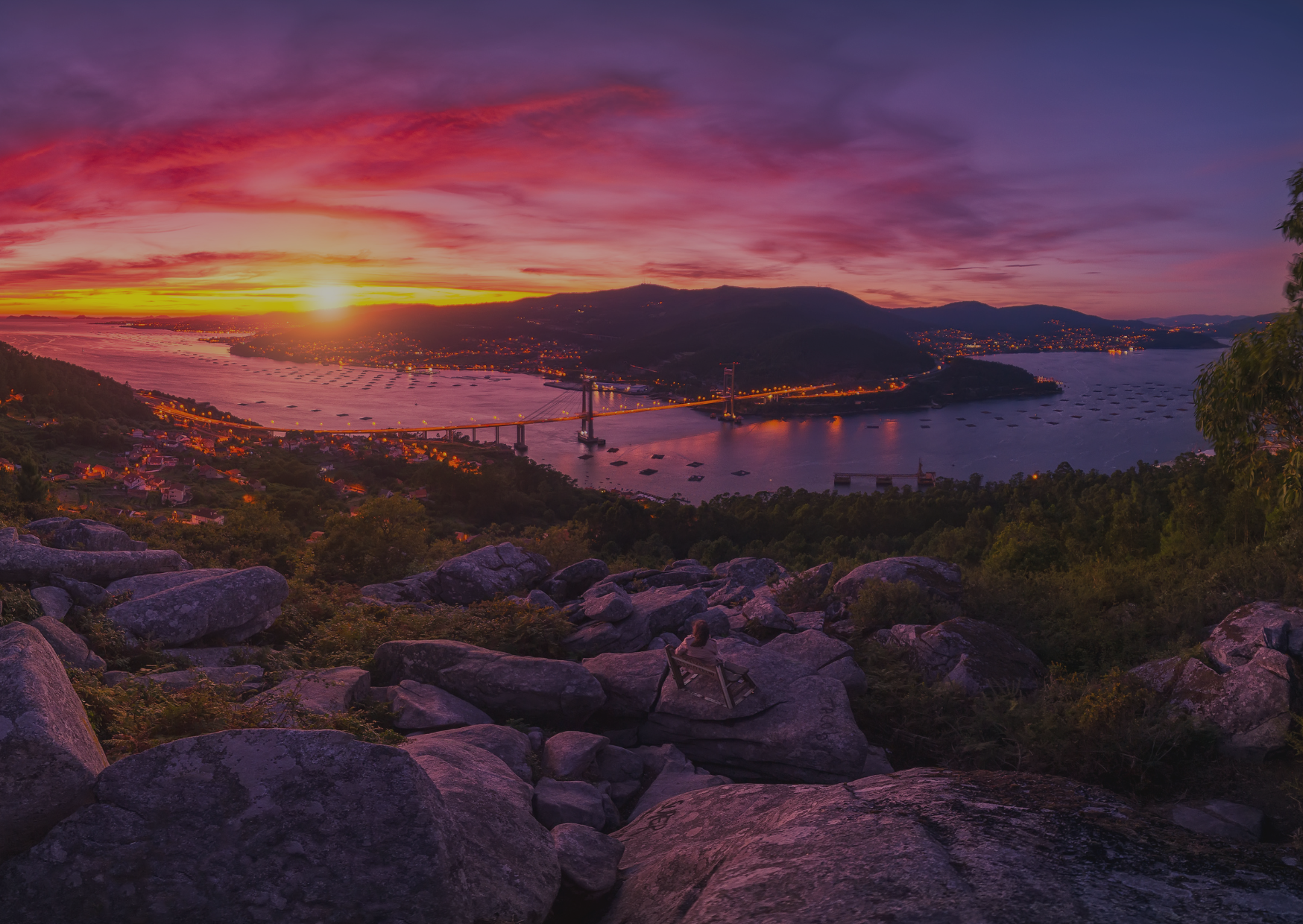 A sunset over a body of water surrounded by mountains and rocks.
