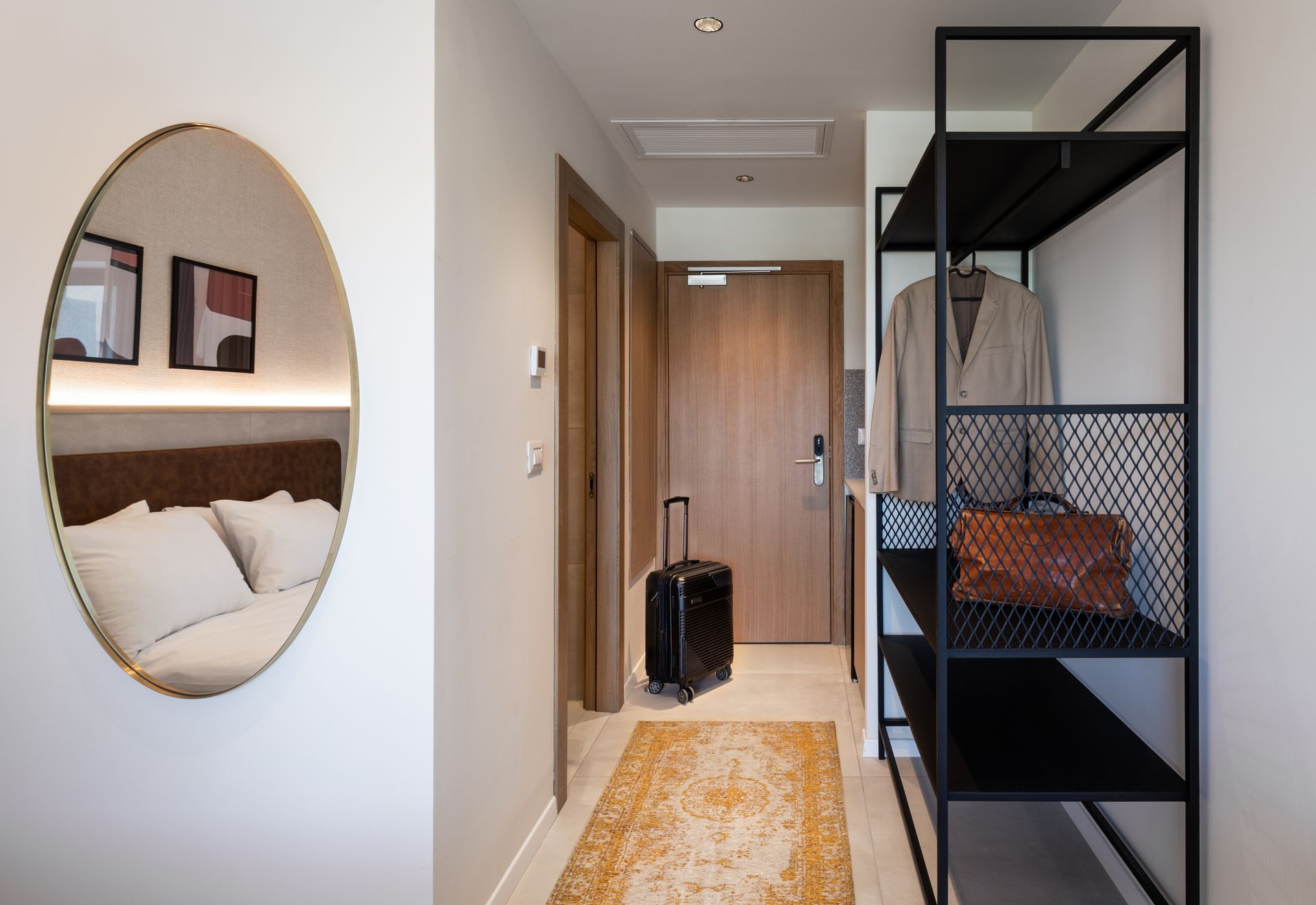 A hotel room with a suitcase and a mirror.