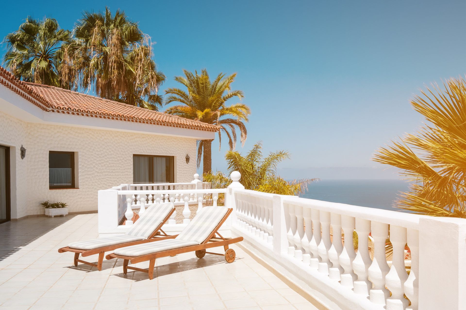 Hay dos sillones en el balcón de una casa con vista al mar.