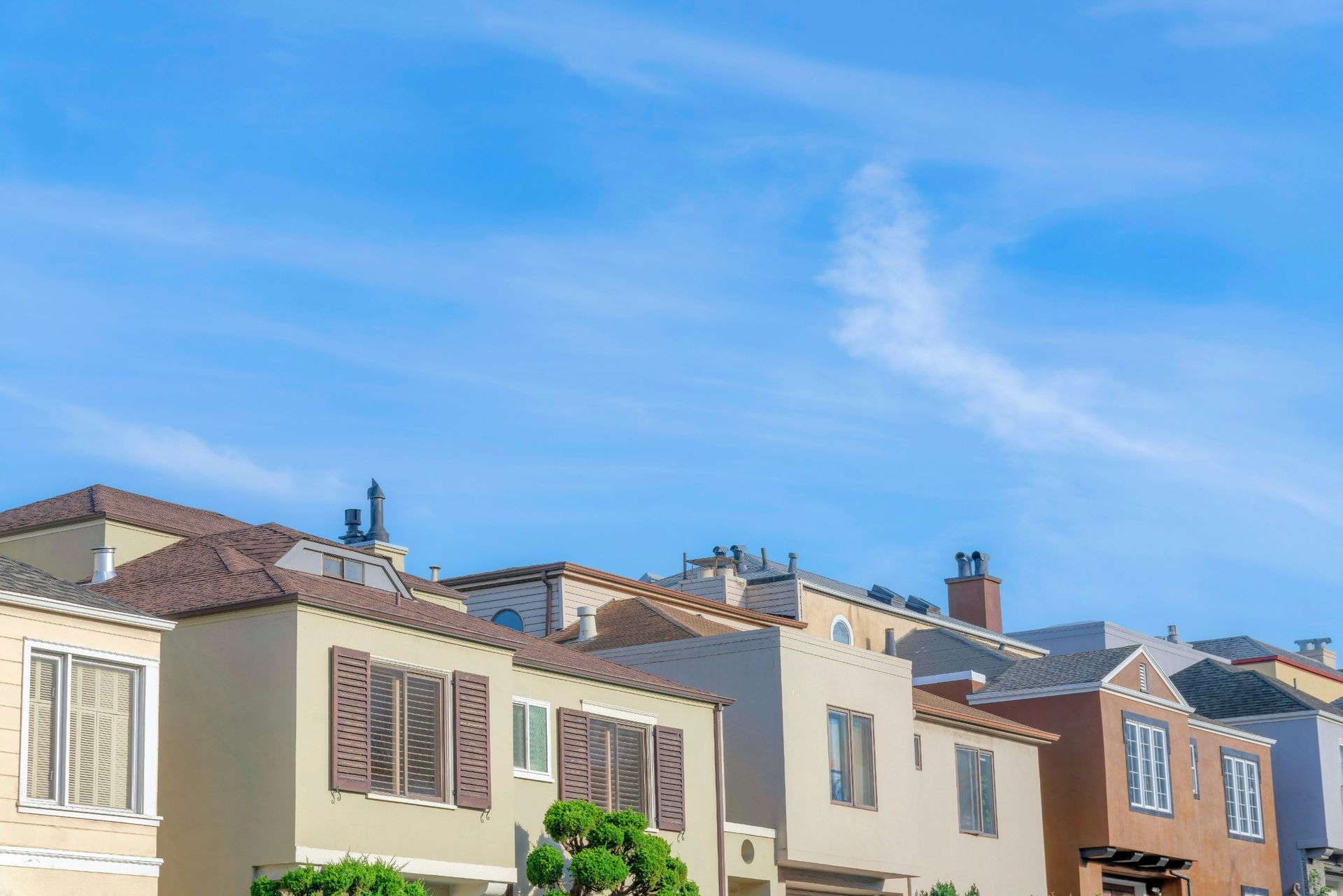 Una hilera de casas en un día soleado con un cielo azul en el fondo.