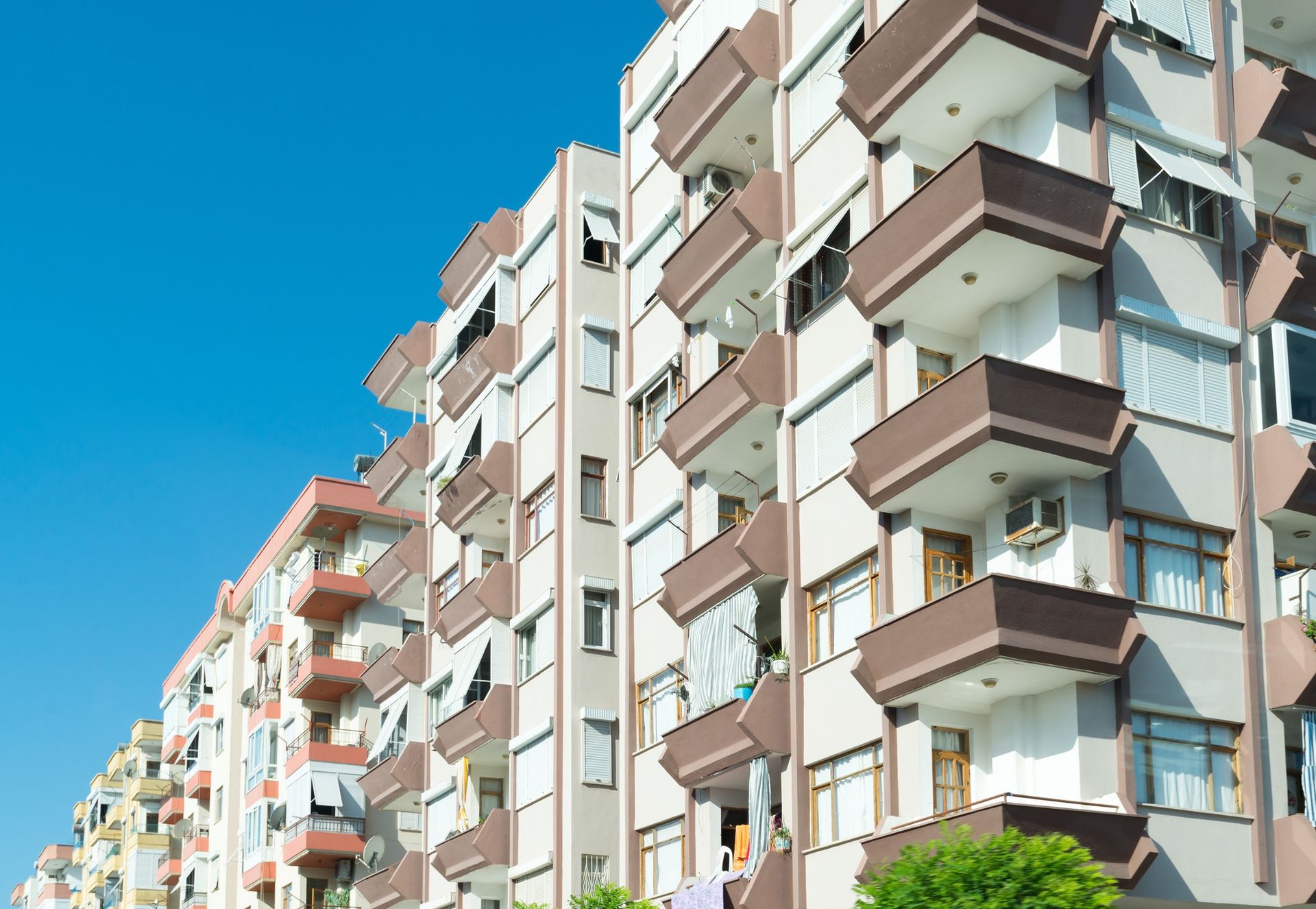 Una hilera de edificios de apartamentos con balcones contra un cielo azul.