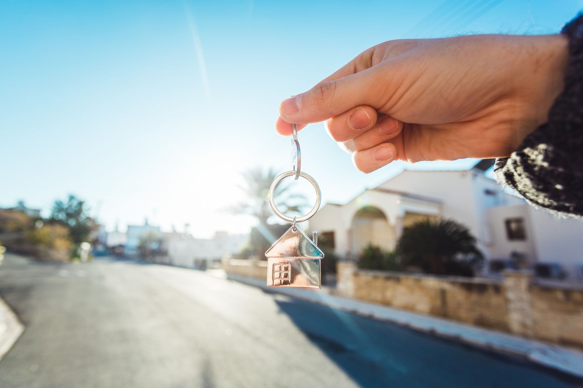 Una persona sostiene un llavero con una casa delante de una casa.