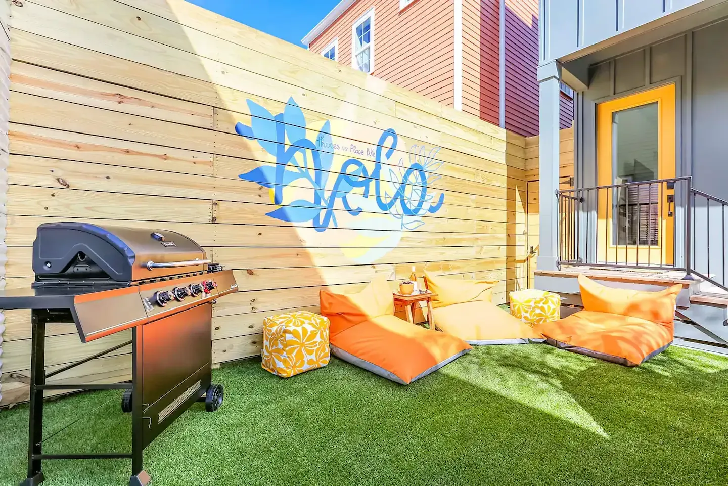 A backyard with a grill , chairs and a sign that says hello.