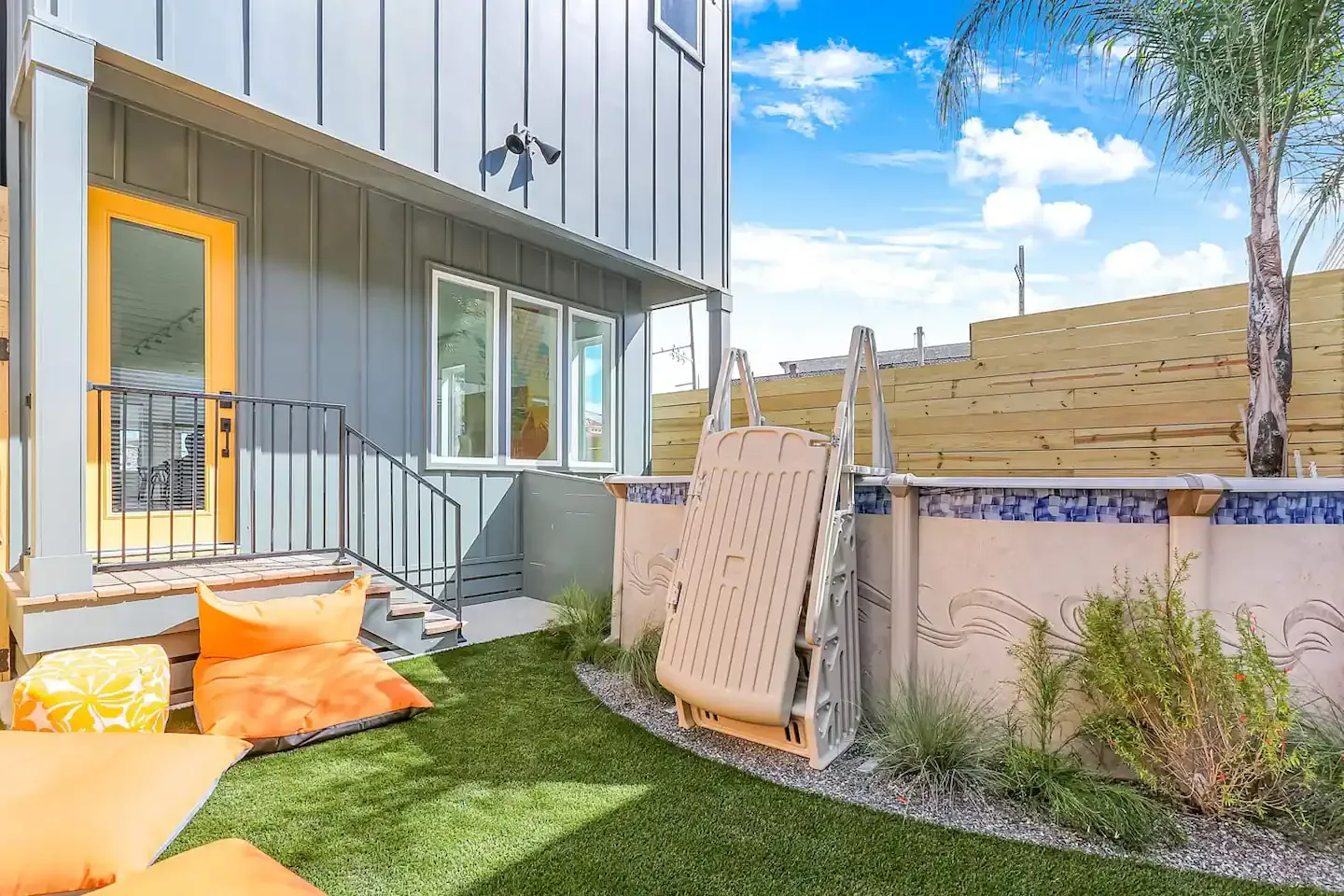 A backyard of a house with a lawn and a yellow door.