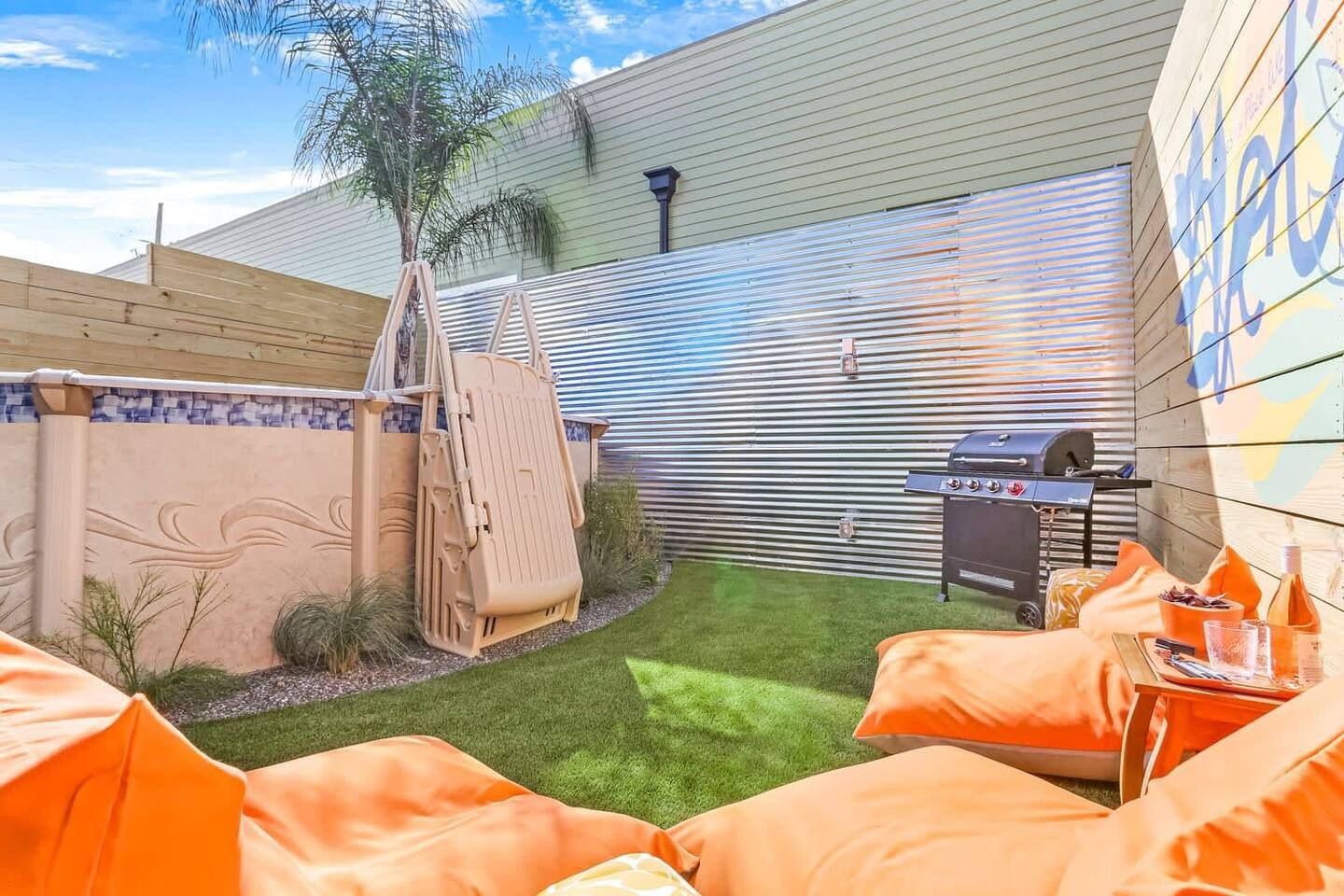 A backyard with orange bean bag chairs and a grill.
