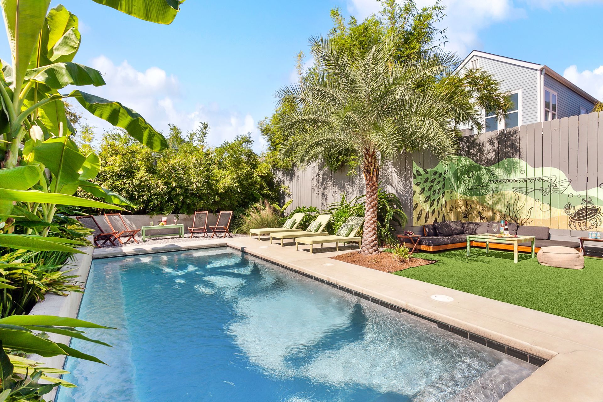 There is a large swimming pool in the backyard of a house.