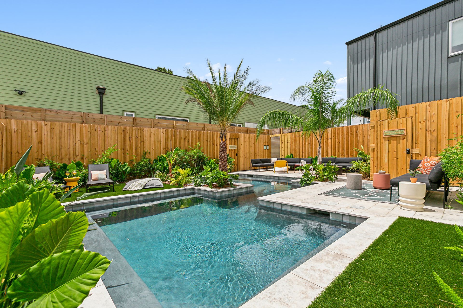 A large swimming pool is surrounded by a wooden fence in a backyard.