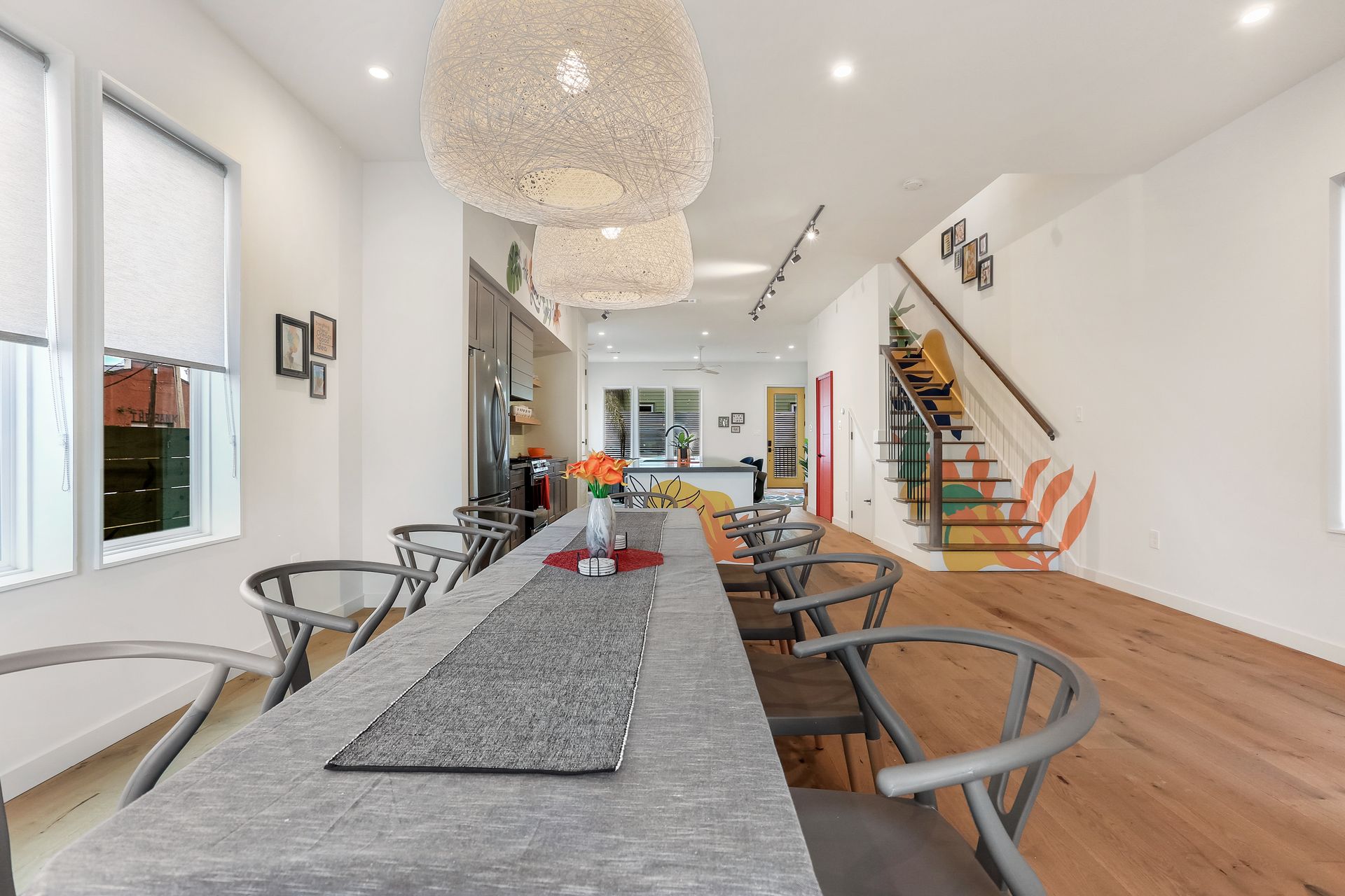 A dining room with a long table and chairs in a house.