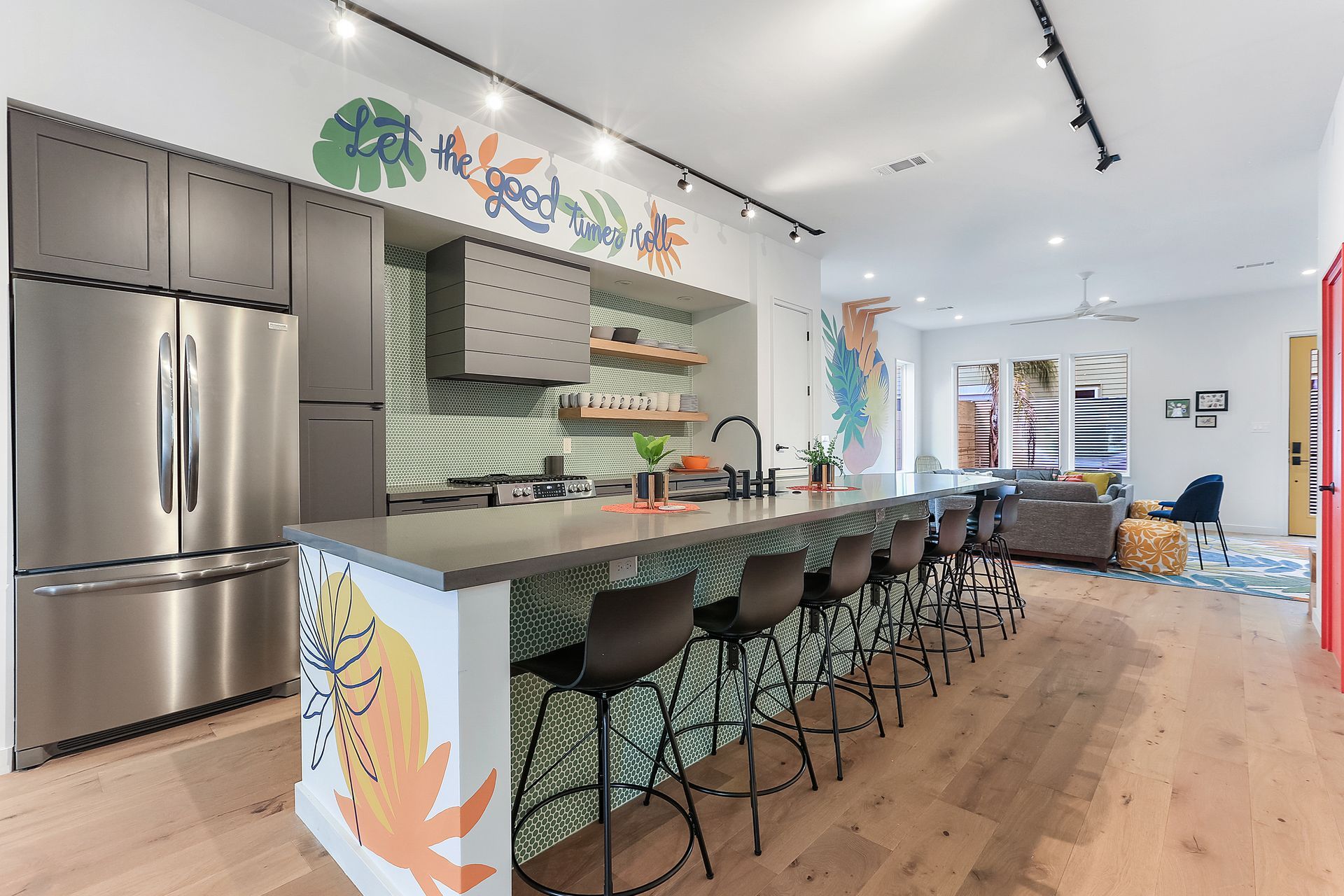 A kitchen with stainless steel appliances and a long island with stools.