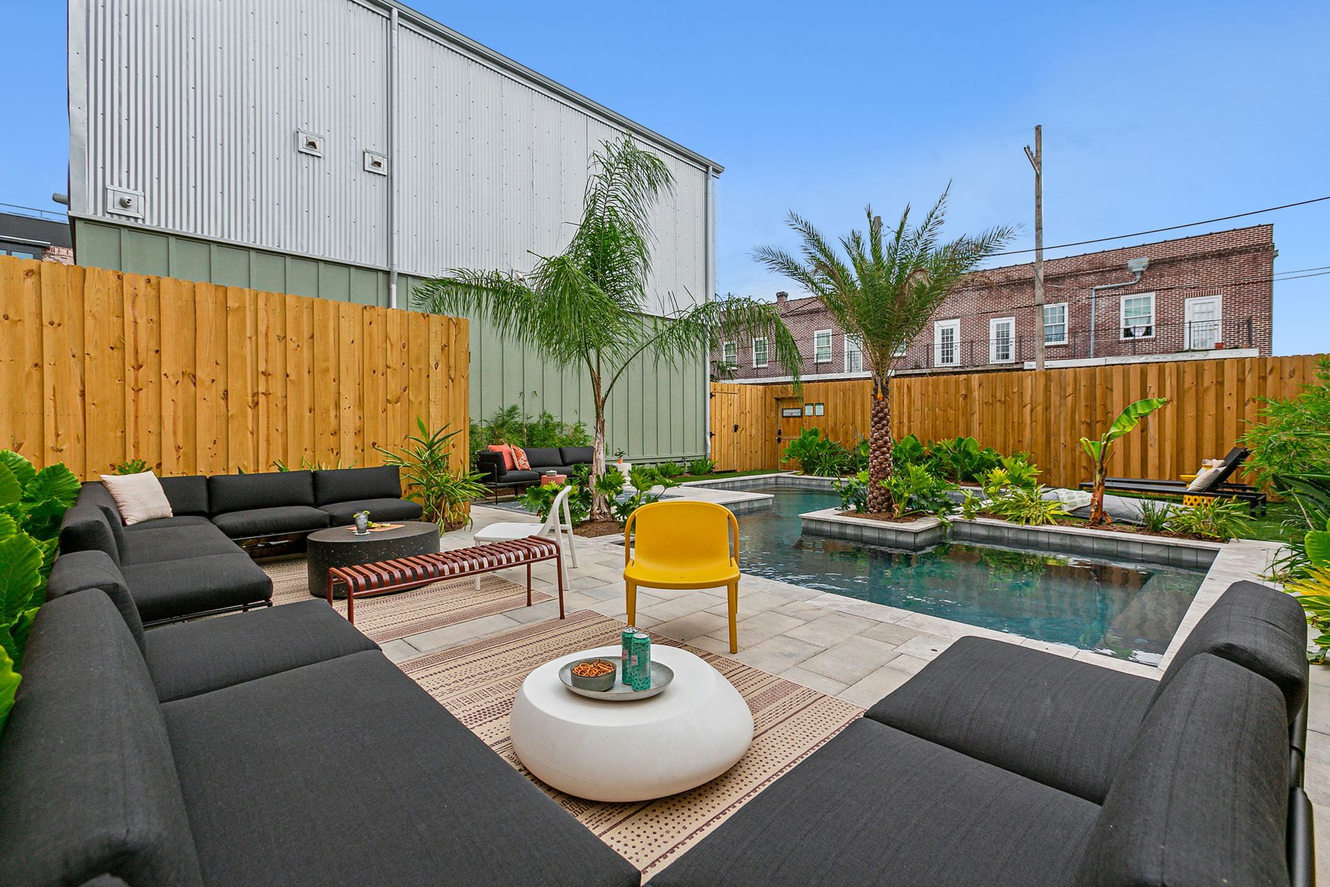 A backyard with a swimming pool , couch , table and chairs.