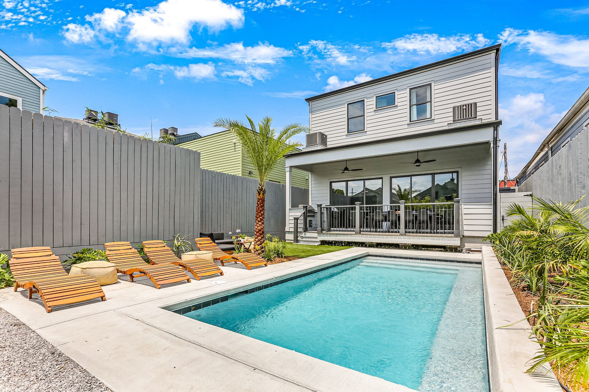 There is a large swimming pool in the backyard of a house.