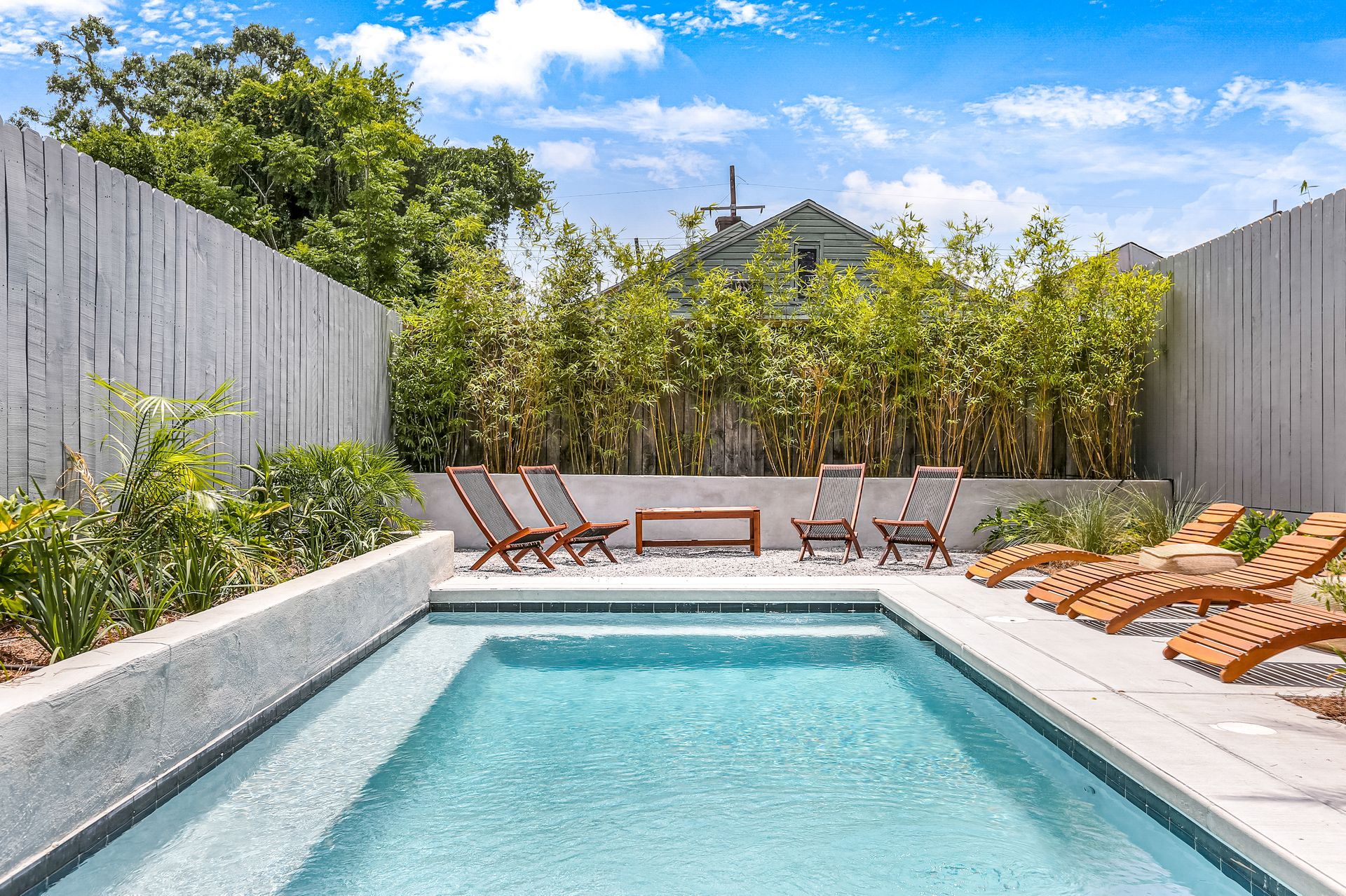 A large swimming pool surrounded by chairs and a fence.
