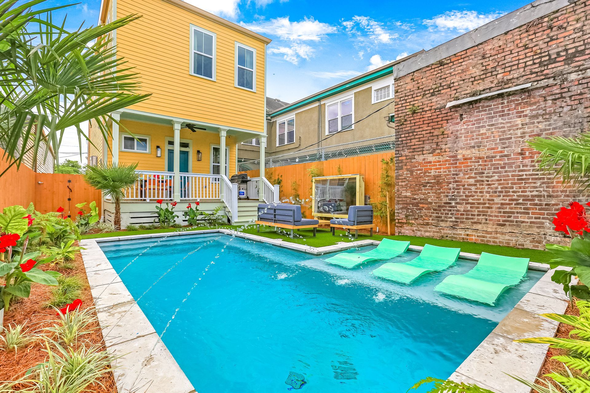 There is a large swimming pool in the backyard of a house.