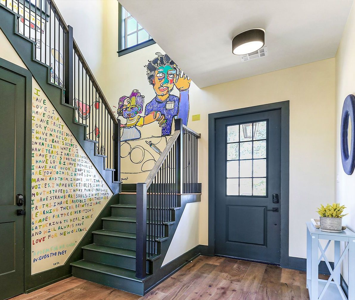 A hallway with a staircase and a door with a painting on the wall.