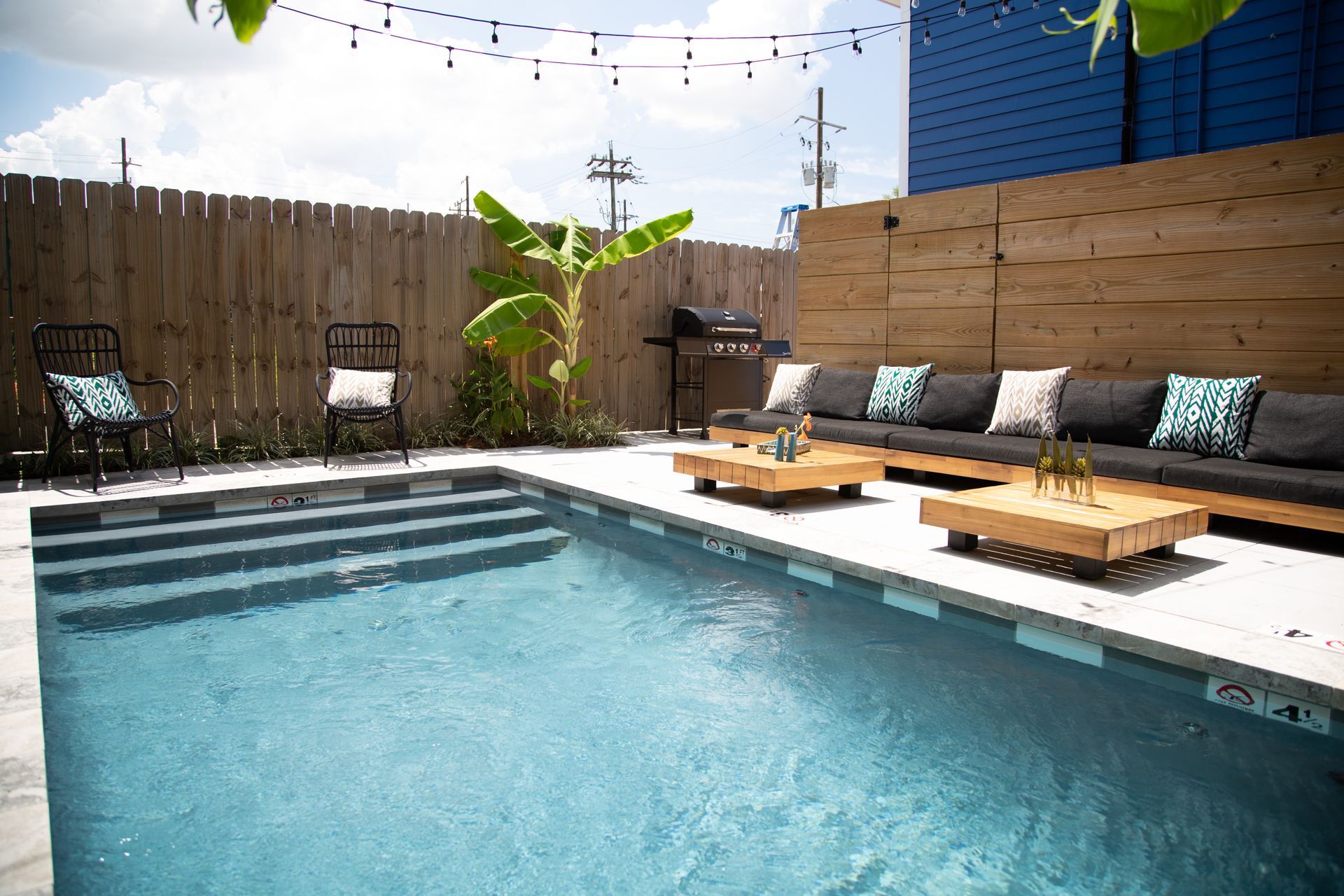 A large swimming pool surrounded by a wooden fence and patio furniture.