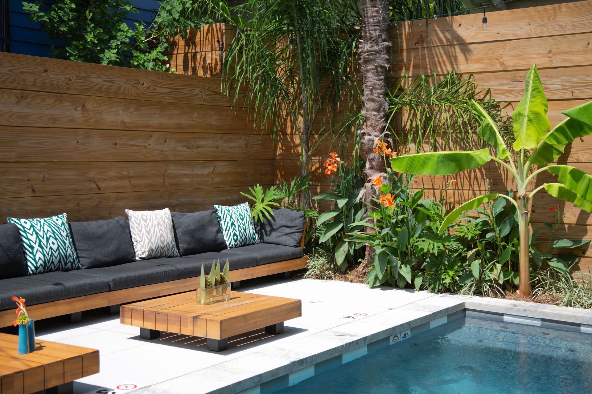 A patio area with a couch and a table next to a swimming pool.