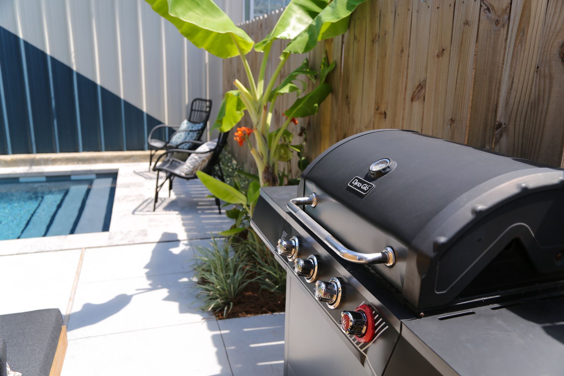 A grill is sitting on a patio next to a pool