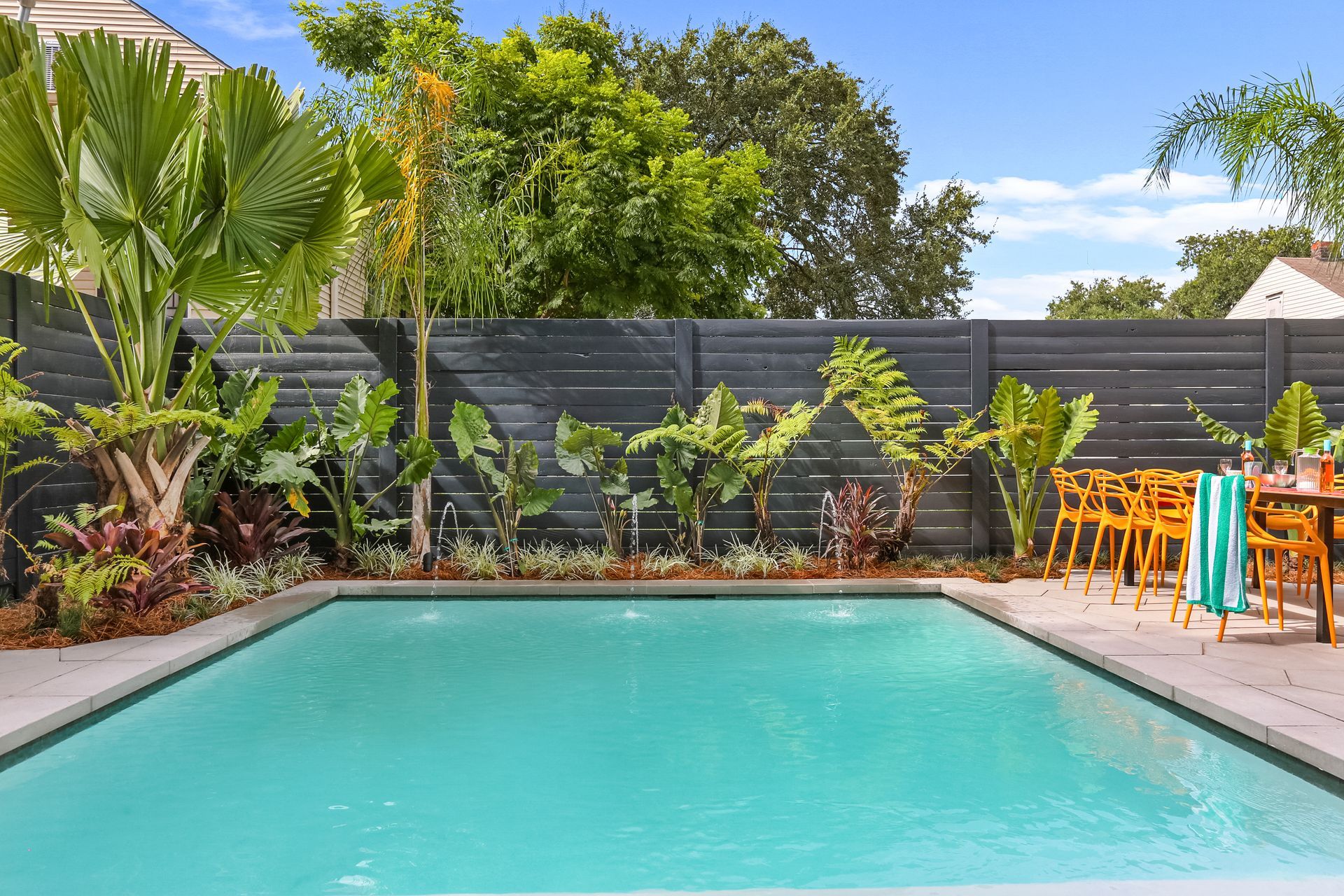There is a large swimming pool in the backyard with a fence surrounding it.