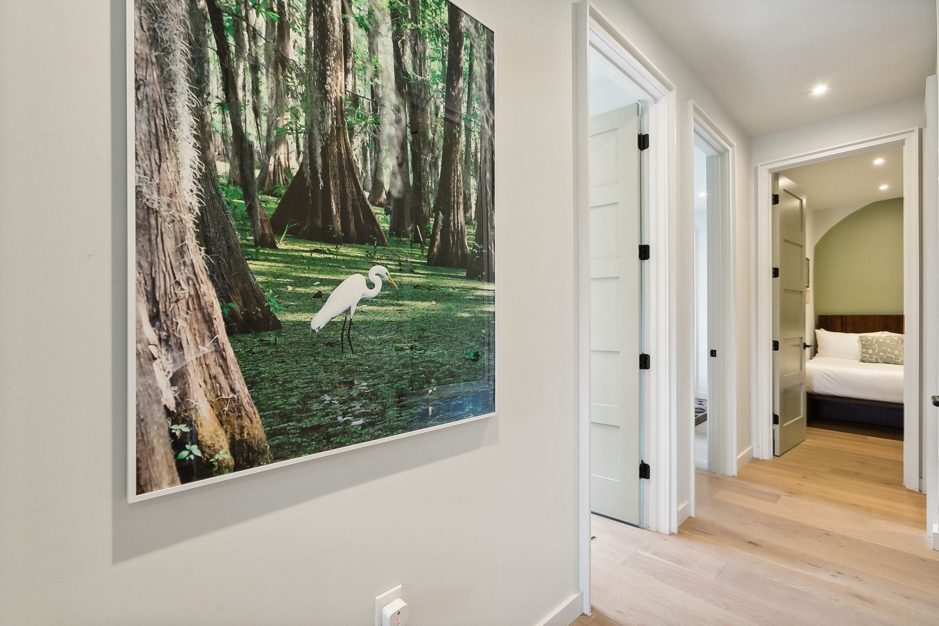 A hallway with a picture of a bird in the woods on the wall