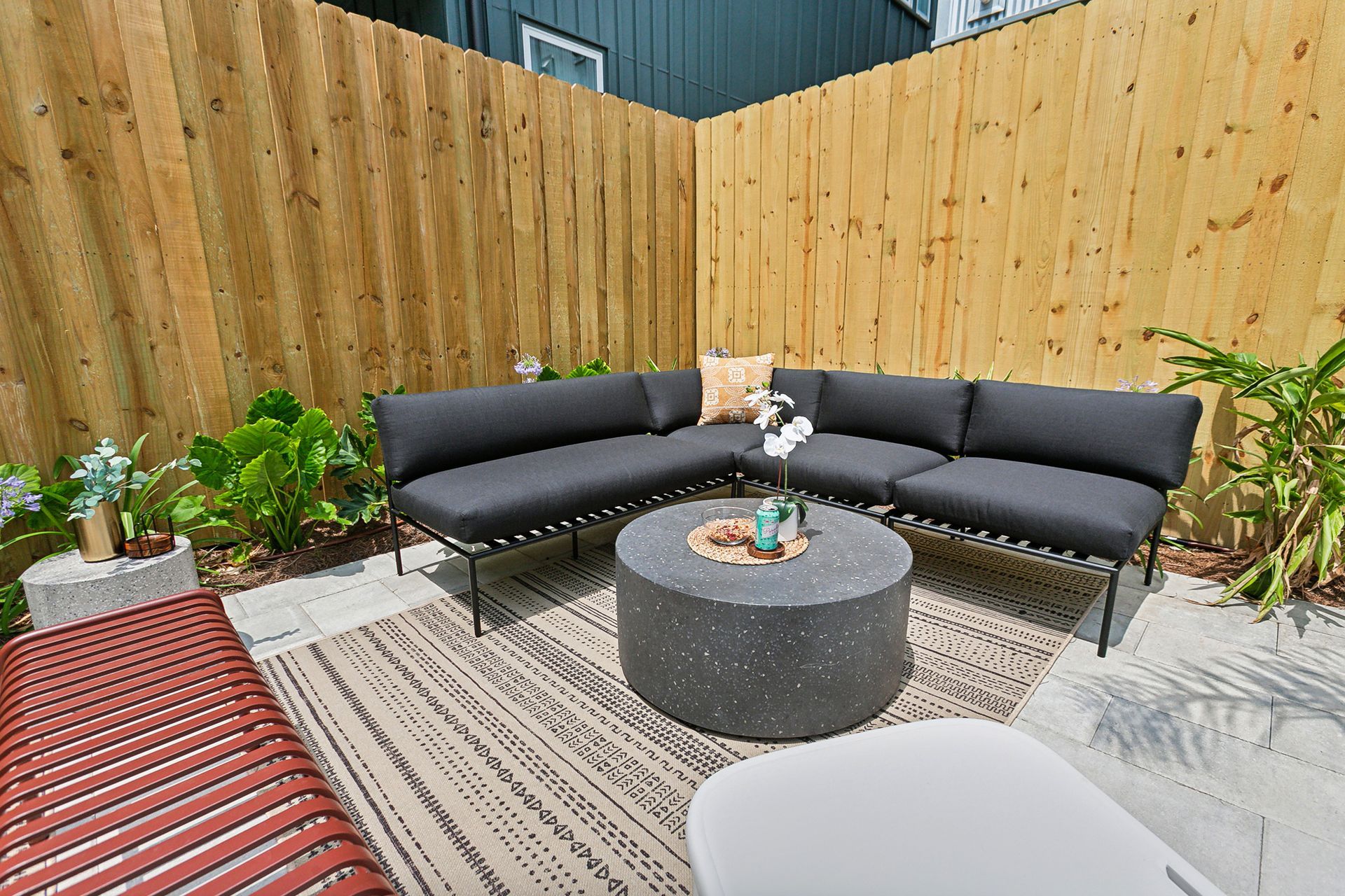 A patio with a couch and a coffee table in front of a wooden fence.