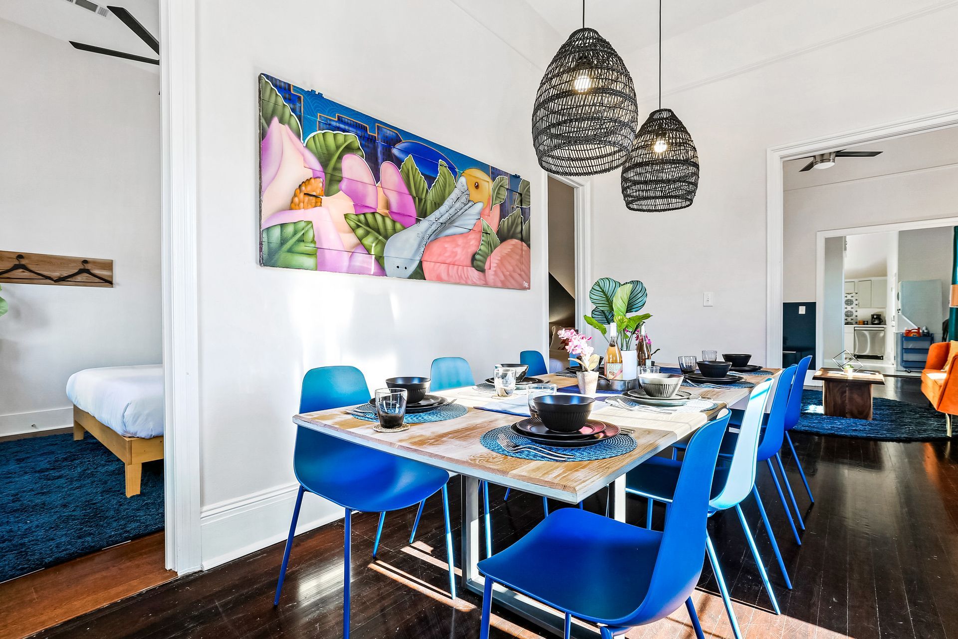 A dining room with a table and chairs and a painting on the wall.