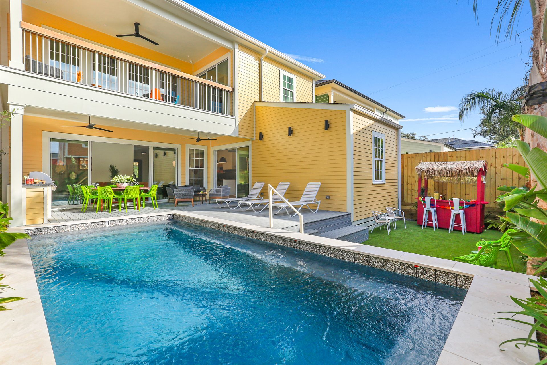 There is a large swimming pool in the backyard of a house.