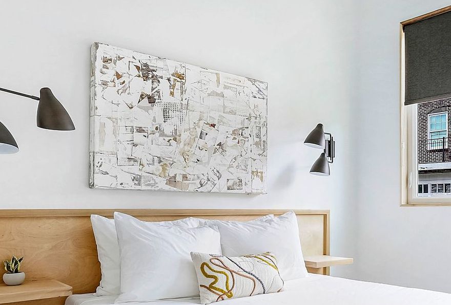 A bedroom with a bed and a painting on the wall above it.