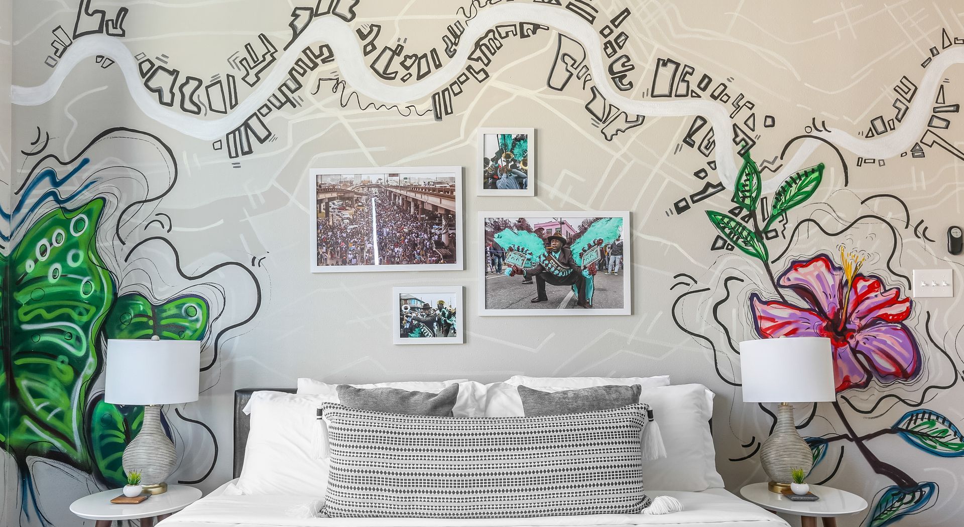 A bedroom with a bed , lamps and a mural on the wall.