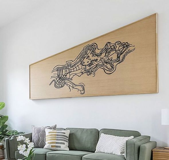 A living room with a green couch and a large painting on the wall above it.