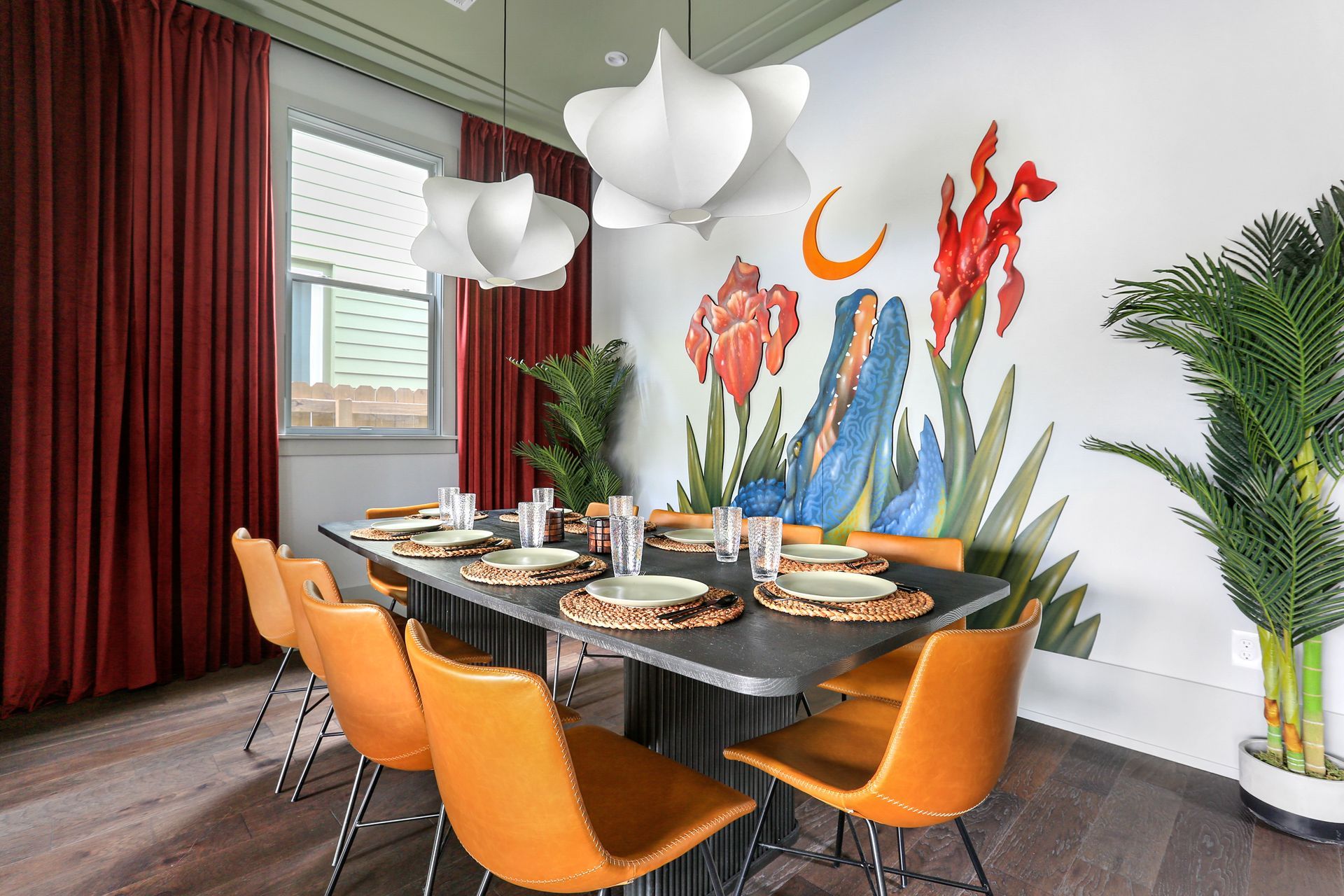 A dining room with a table and chairs and a mural on the wall.