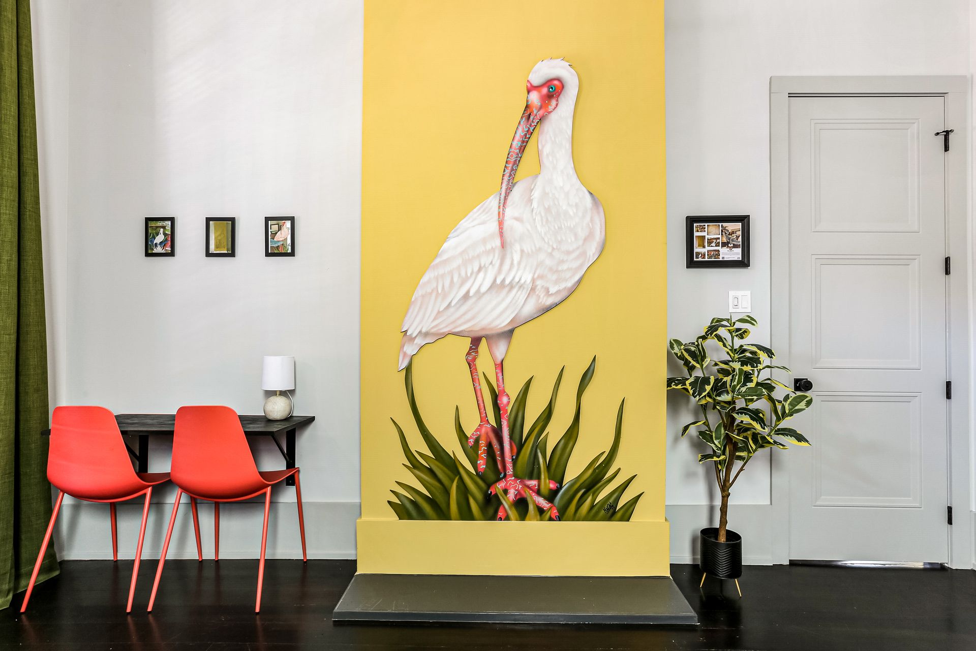 A room with a painting of a bird on the wall.