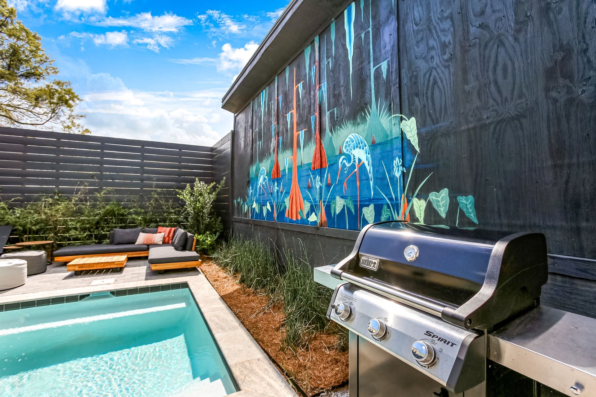 A grill is sitting next to a swimming pool in a backyard.