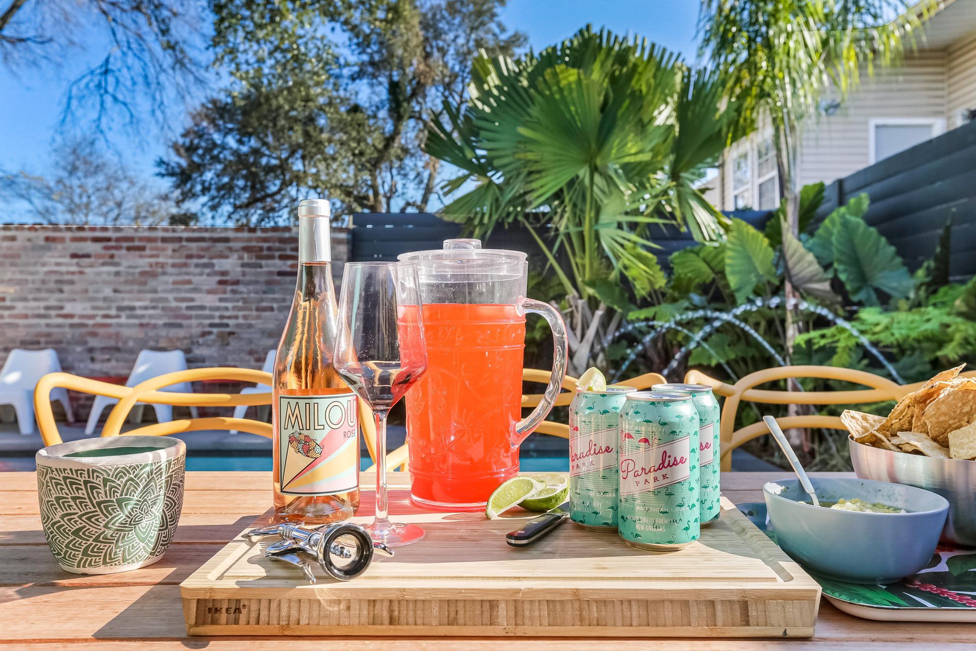 A table with a bottle of wine , a pitcher of drink , and cans of soda.