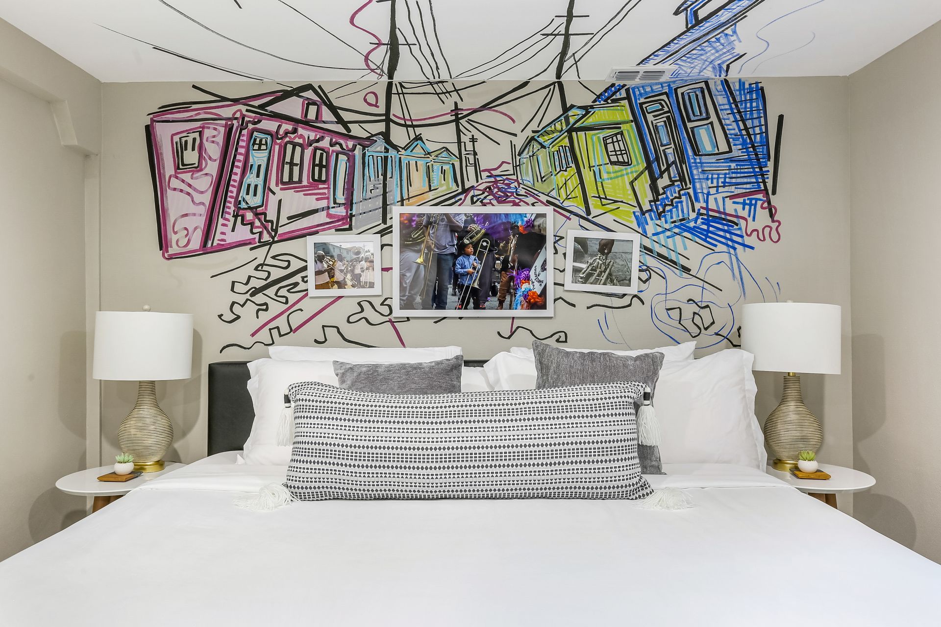 A bedroom with a bed , lamps , and a painting on the wall.