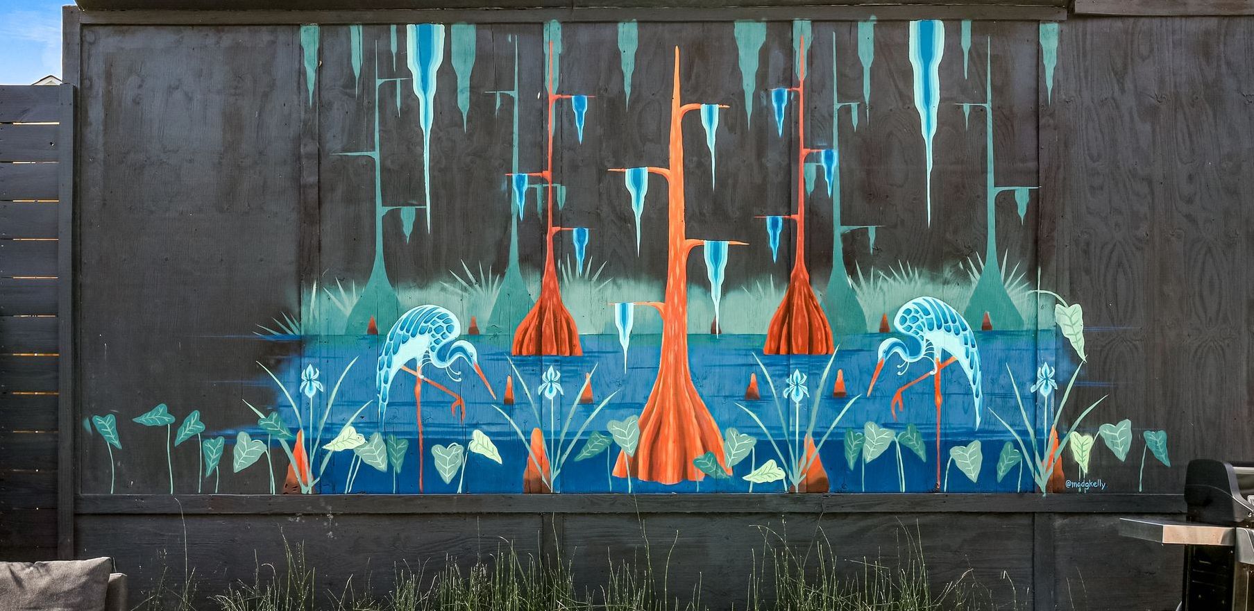 A large painting on a wall of a lake with boats and trees.