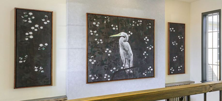 A painting of a bird is hanging on a wall in a room.