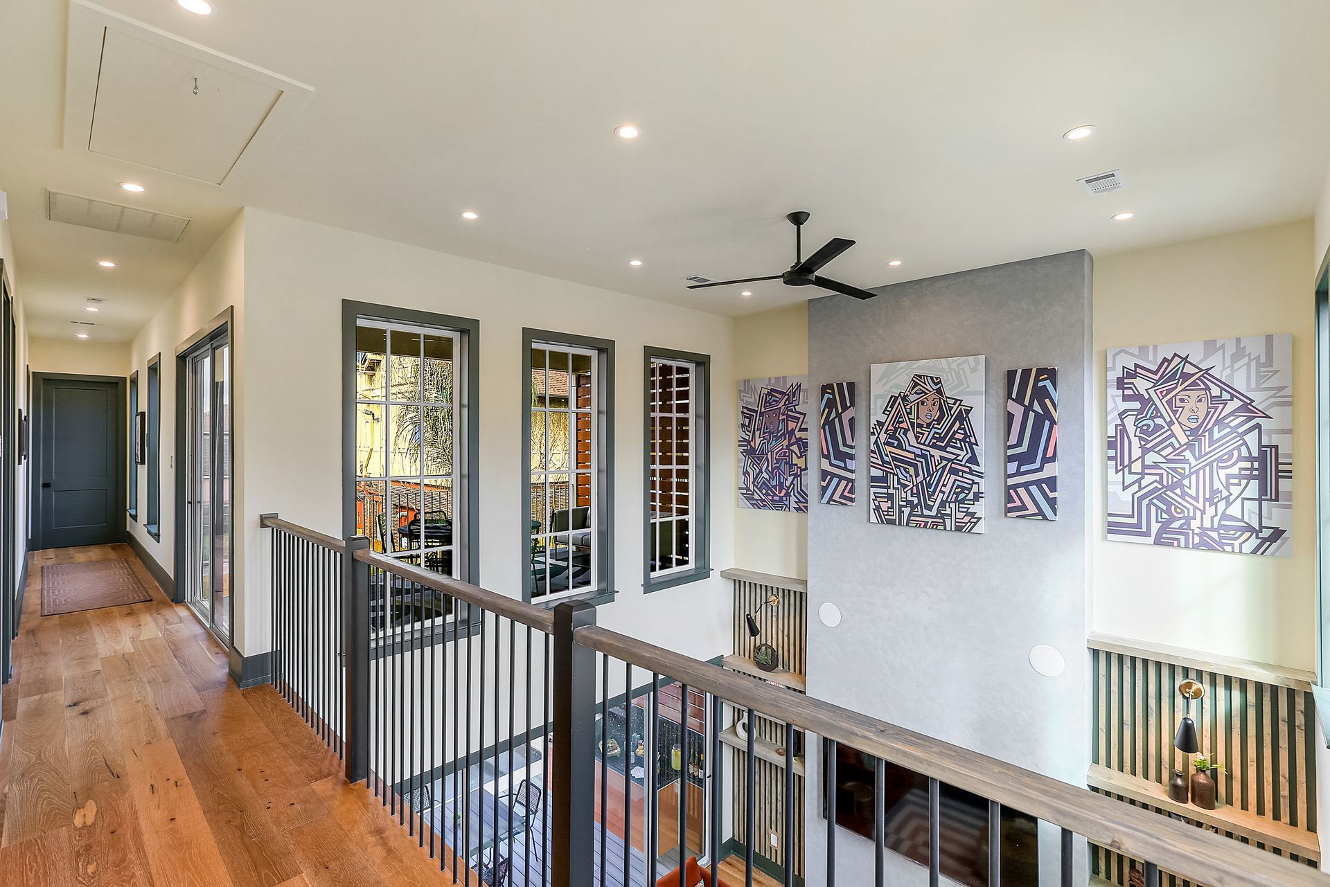 A hallway in a house with a balcony and a ceiling fan.