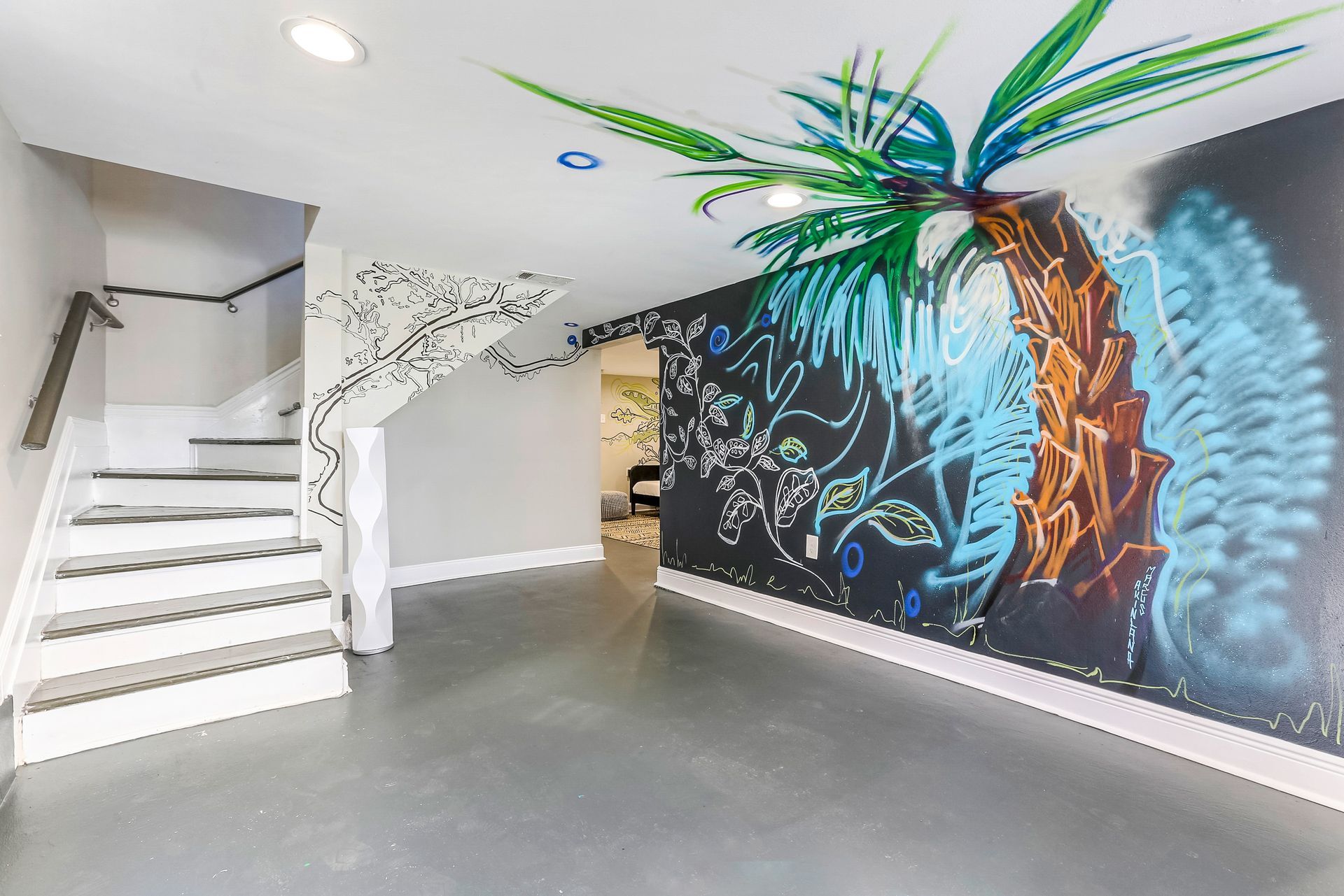A room with stairs and a large mural on the wall.
