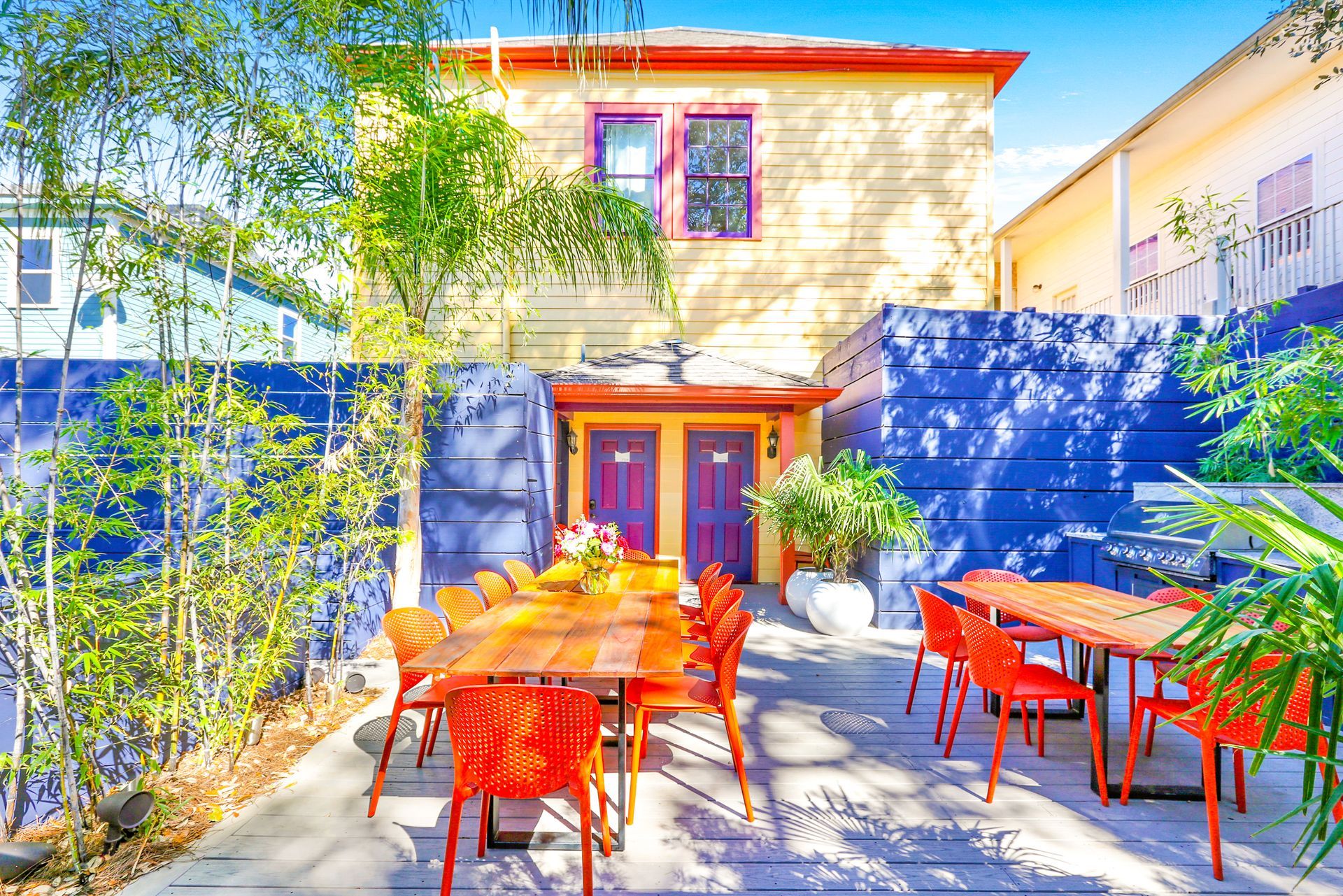 A colorful house with a patio with tables and chairs in front of it.