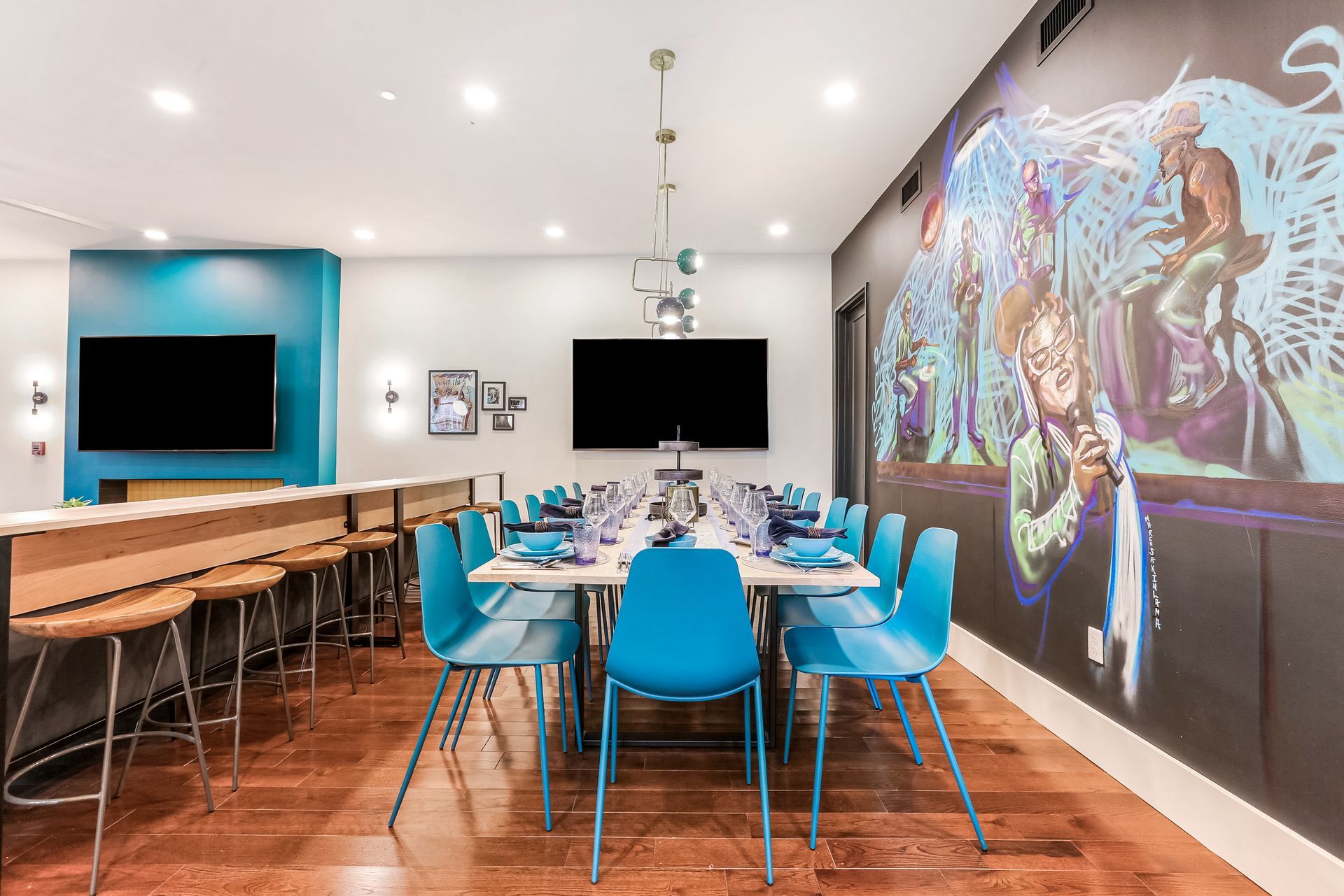 A dining room with a long table and chairs and a mural on the wall.
