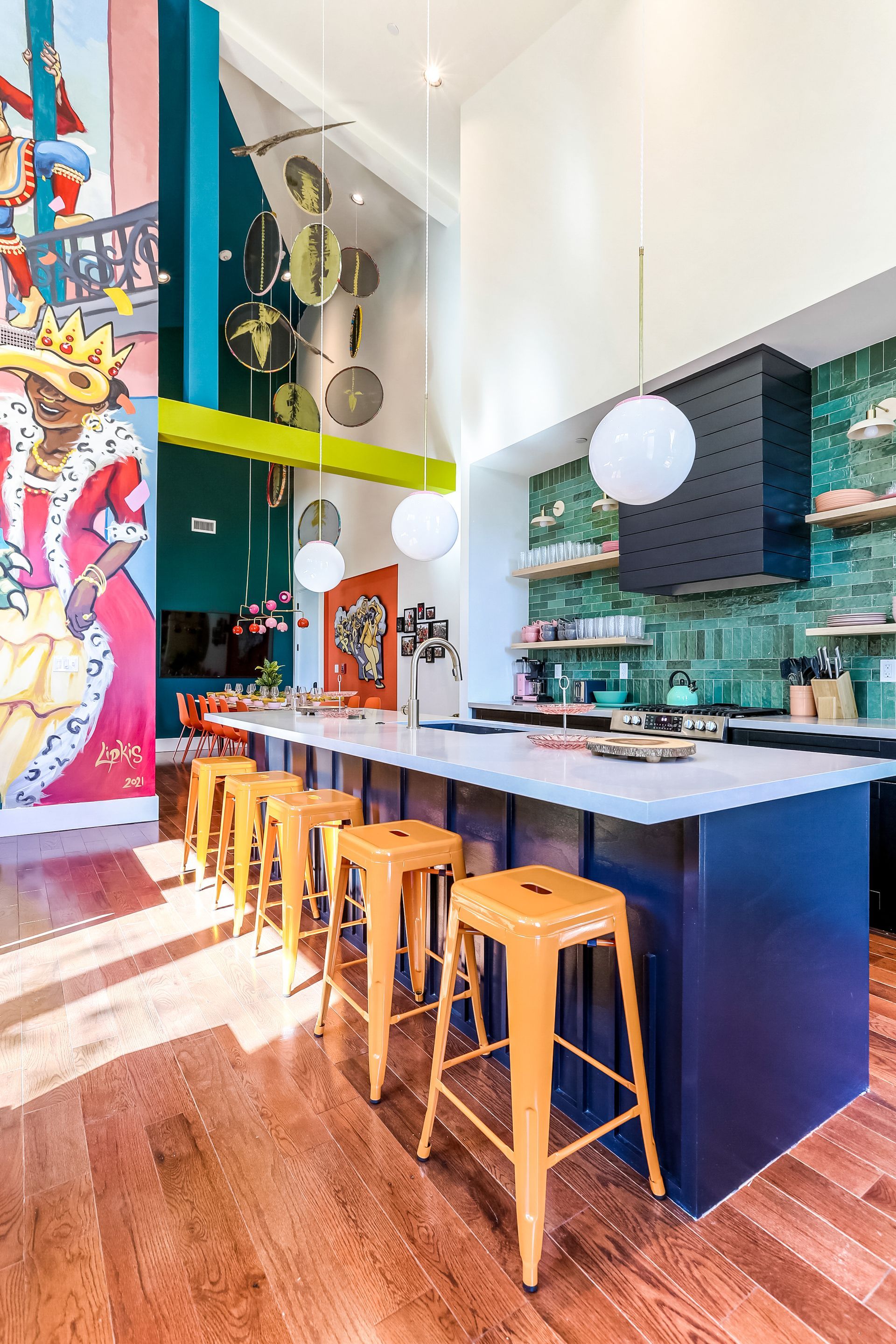 A kitchen with a large island and stools and a painting on the wall.