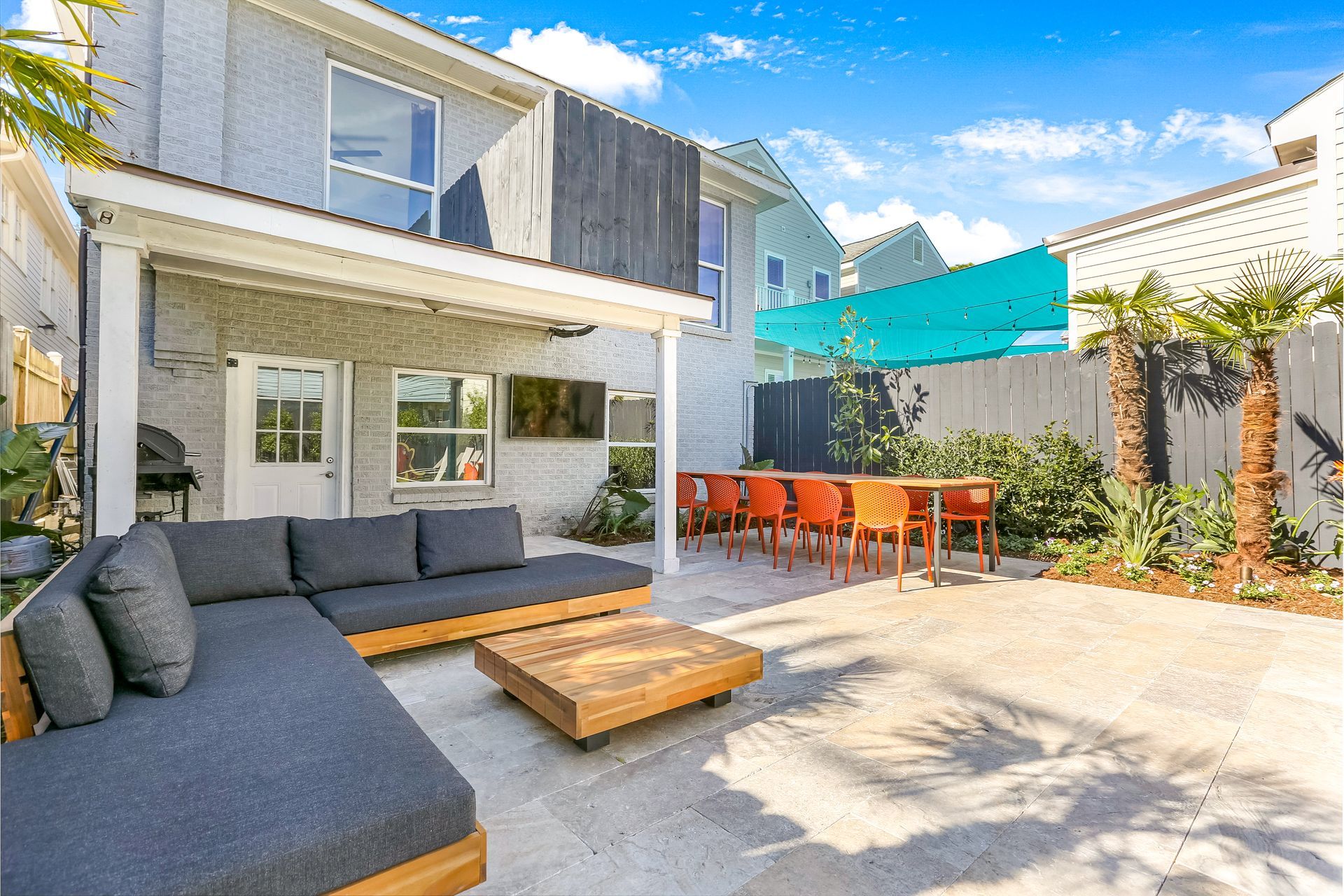 A patio with a couch , table and chairs in front of a house.