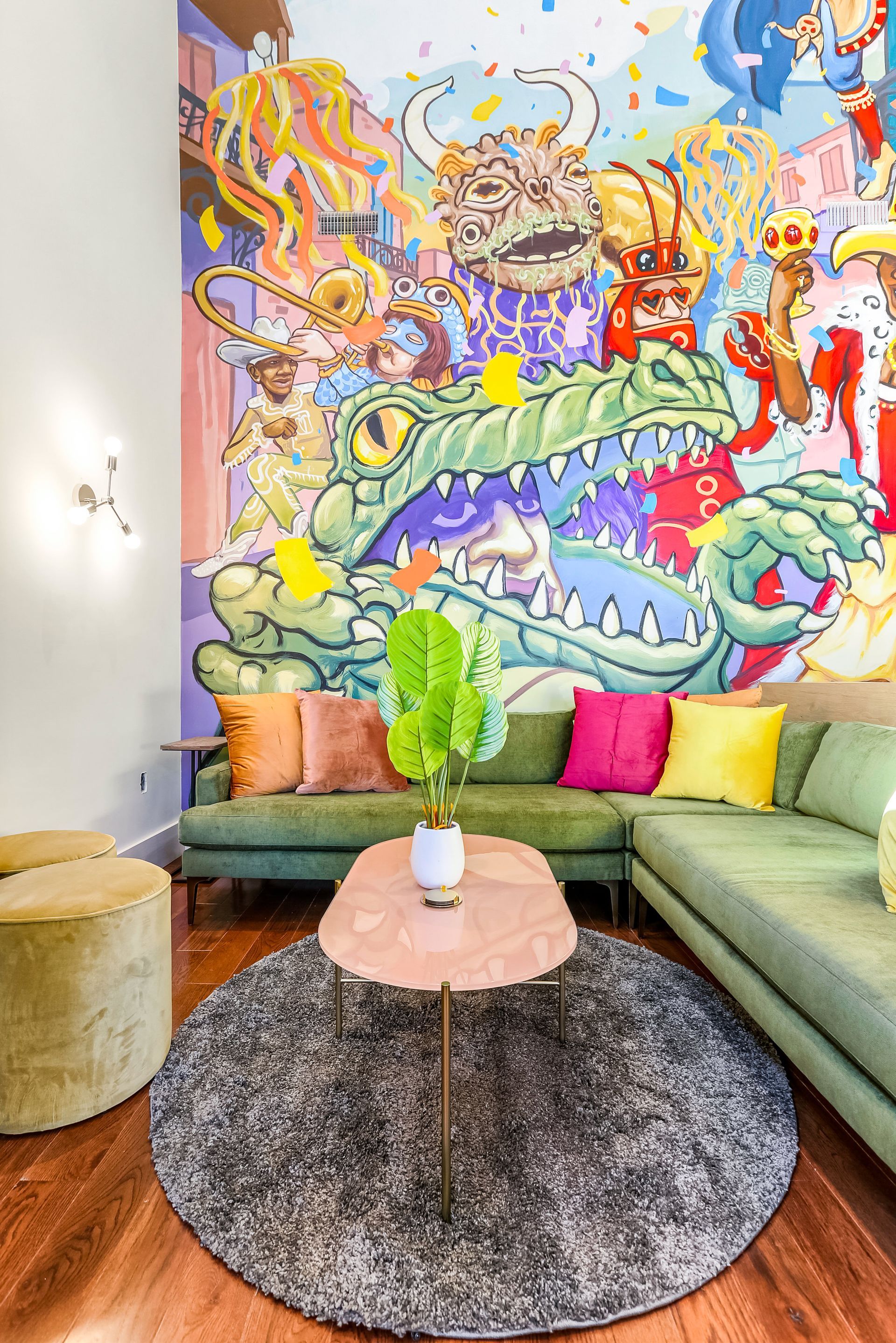 A living room with two couches , a coffee table , and a mural on the wall.