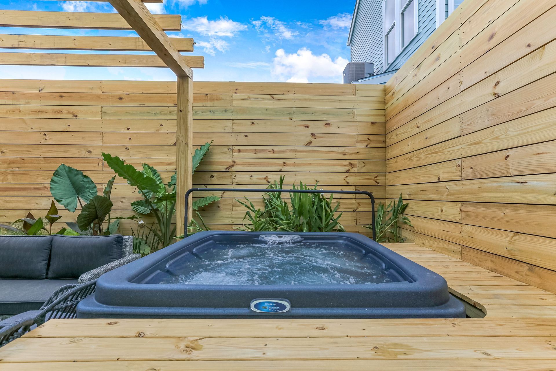 A hot tub is sitting on top of a wooden deck next to a wooden fence.