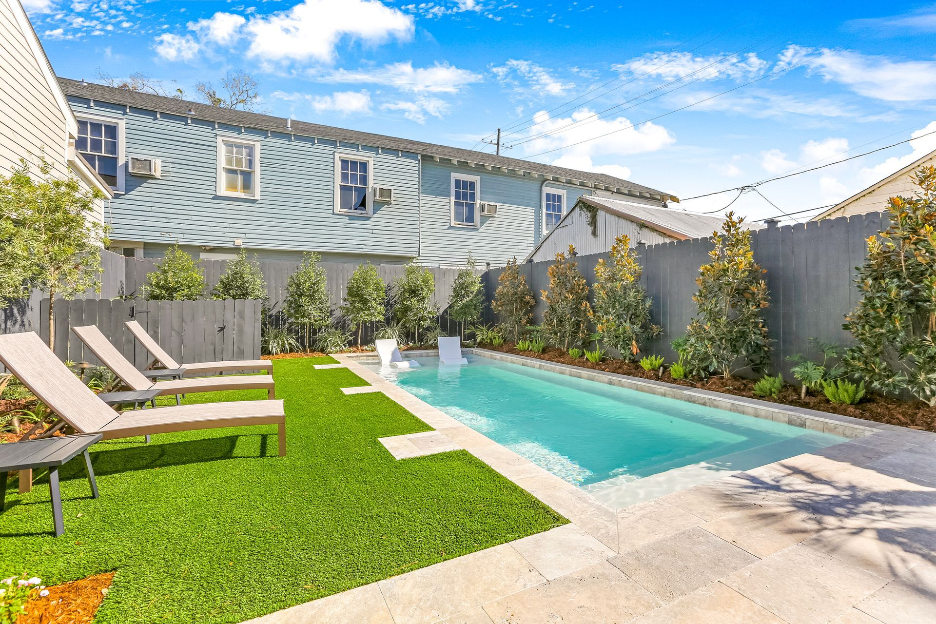 There is a large swimming pool in the backyard of a house.