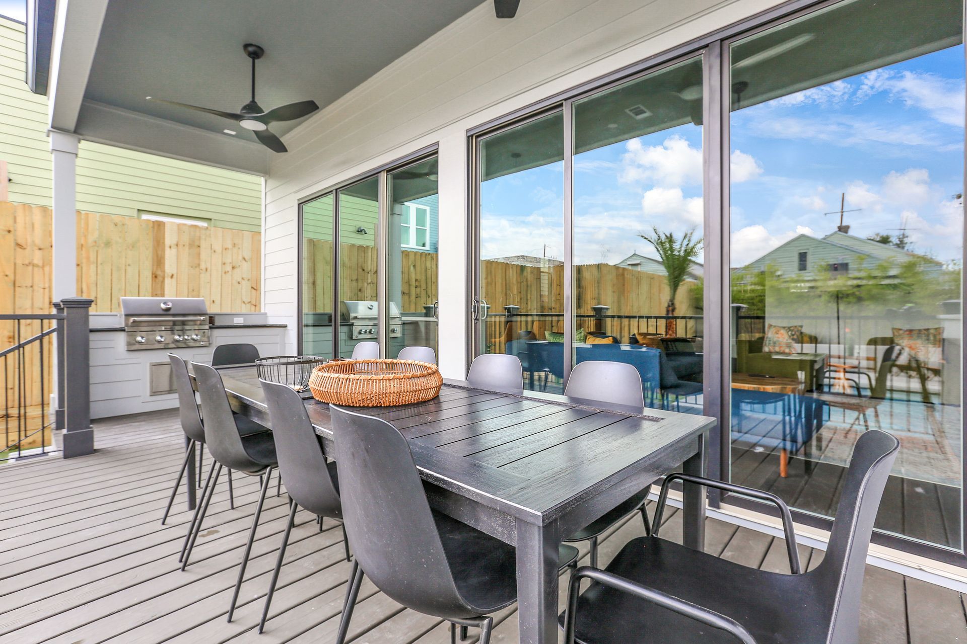 There is a table and chairs on the deck of a house.