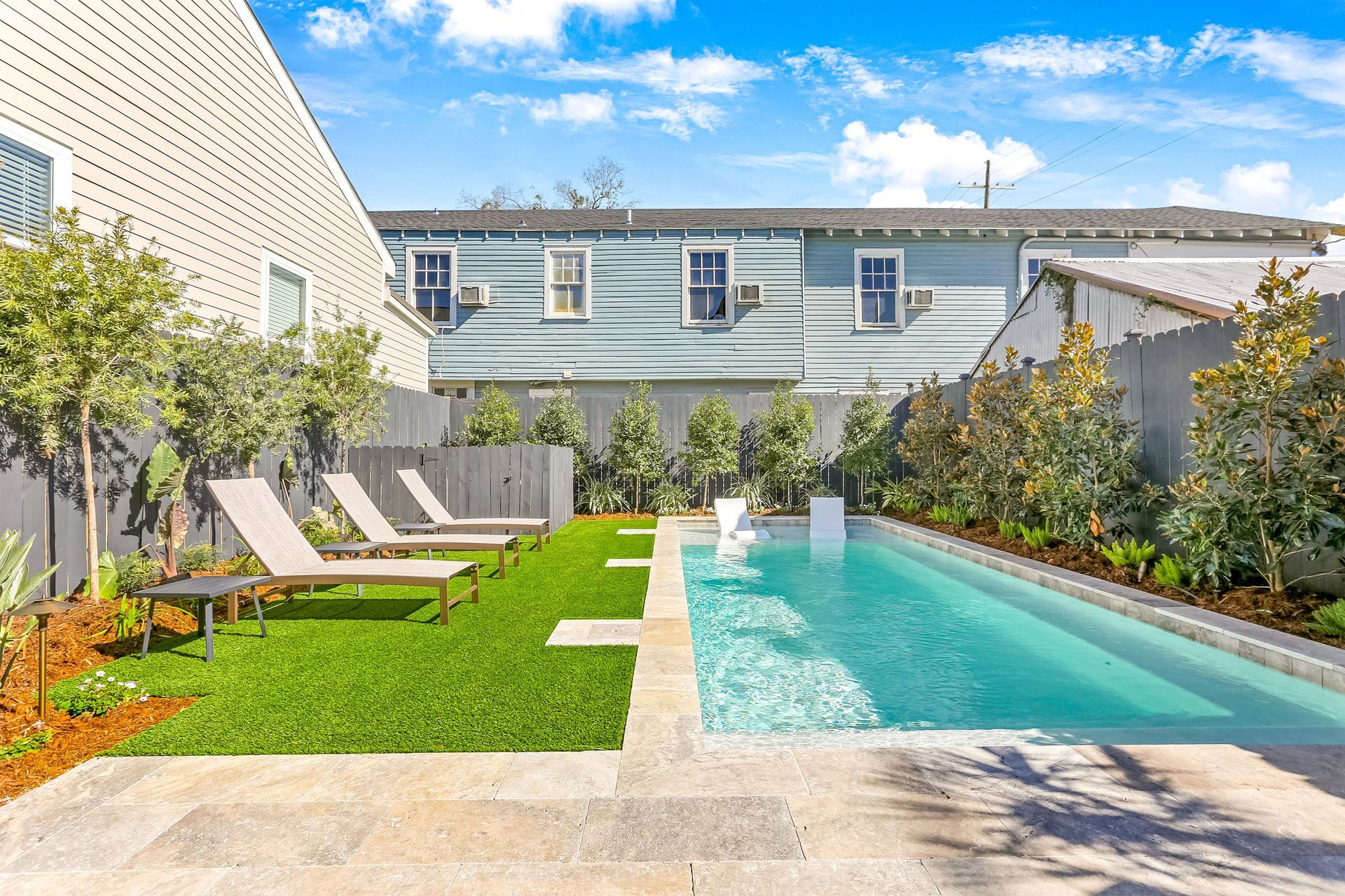 There is a large swimming pool in the backyard of a house.