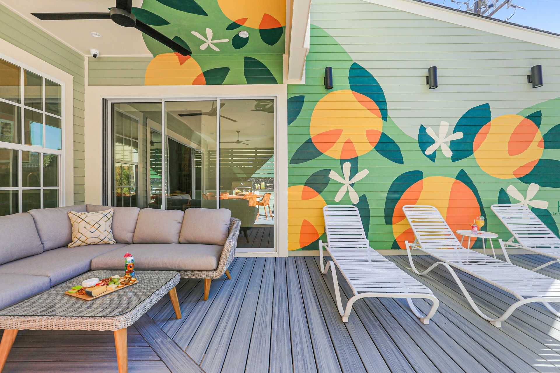 A patio with a couch , table , chairs and a mural on the wall.