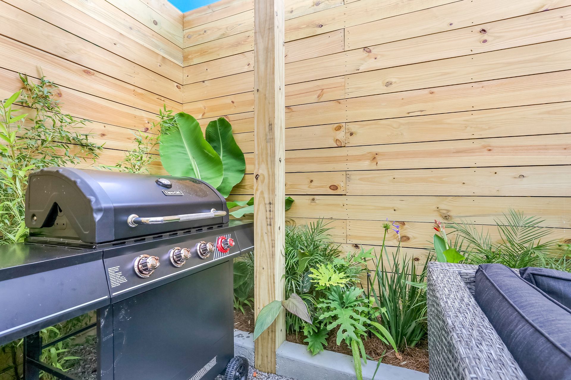 A grill is sitting in a backyard next to a wooden fence.