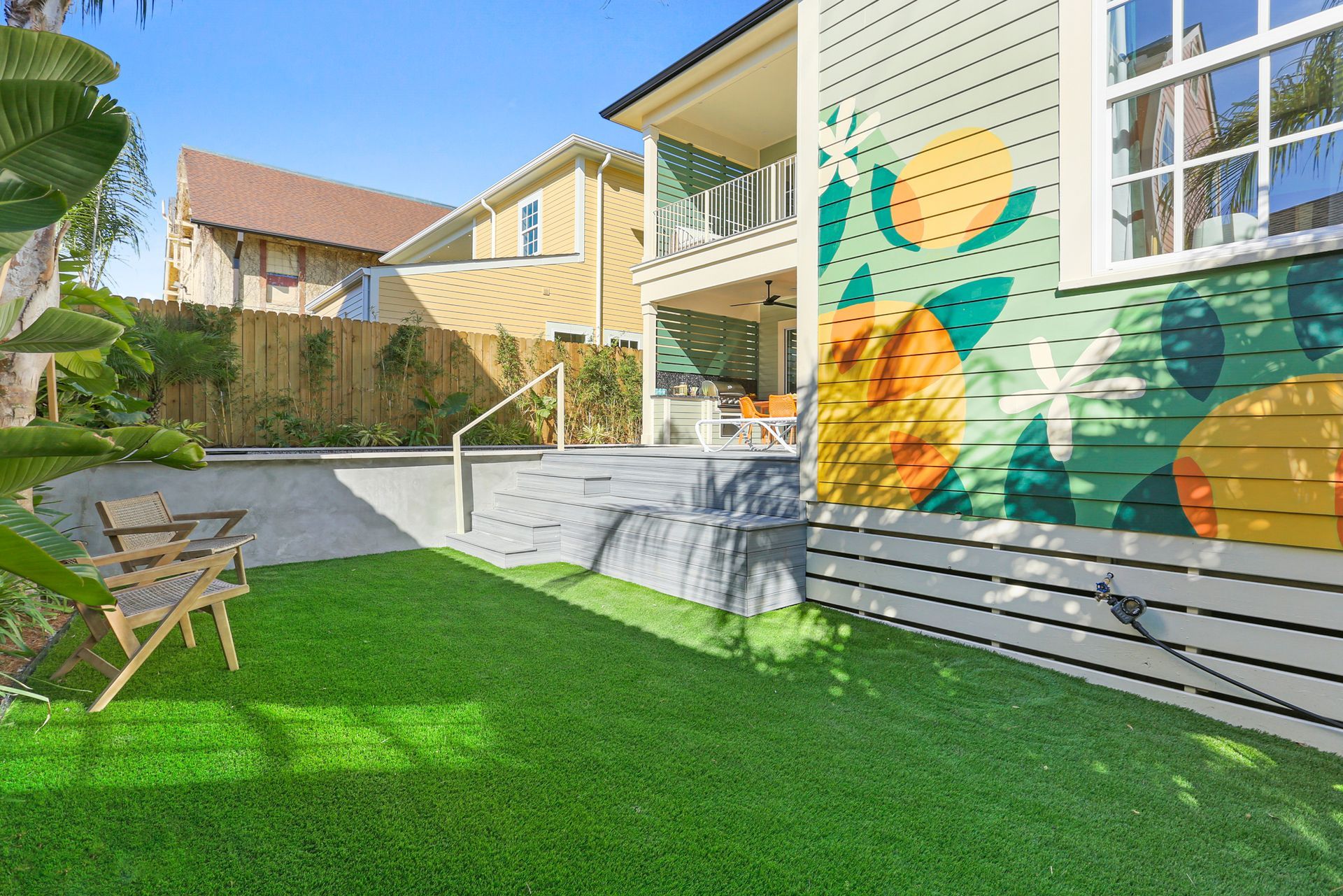 A house with a mural on the side of it and a lawn in front of it.